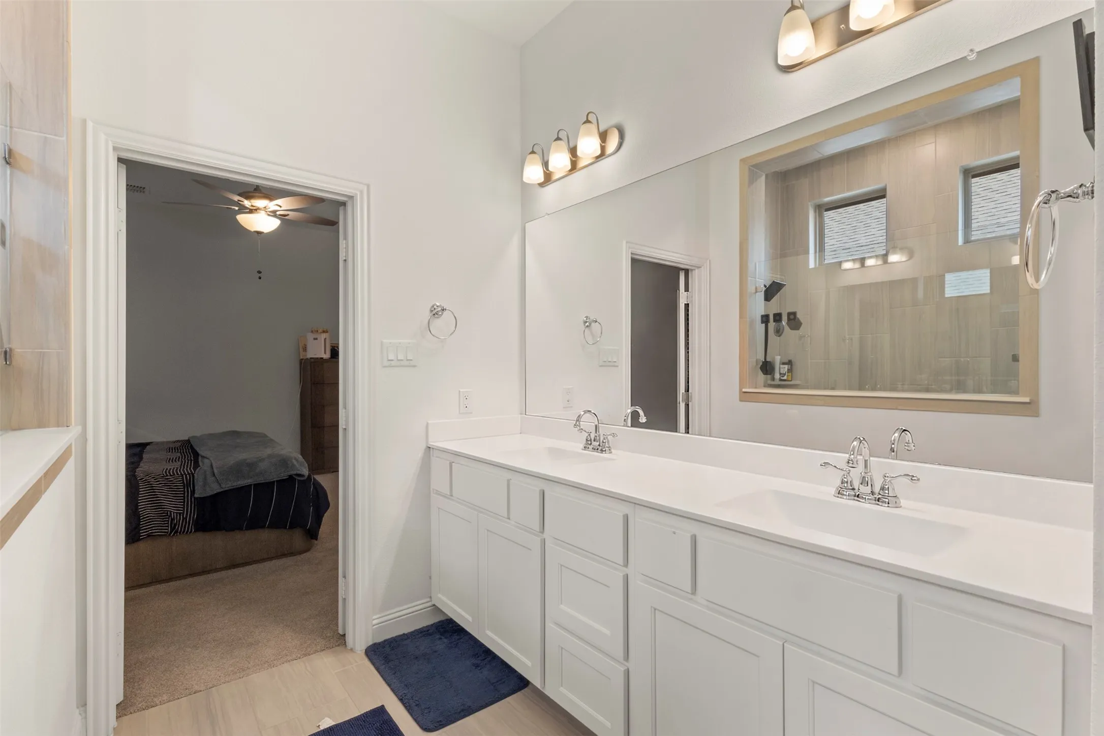 Dual vanity with white cabinetry, integrated sinks, chrome fixtures, and a large wall-mounted mirror