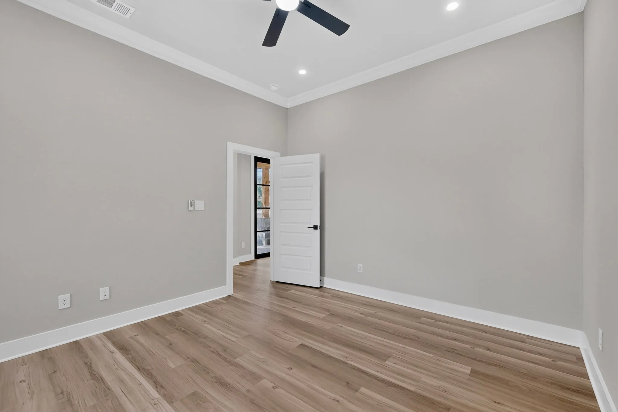 Wood-finish flooring, crown molding, ceiling fan, recessed lighting, and a paneled door