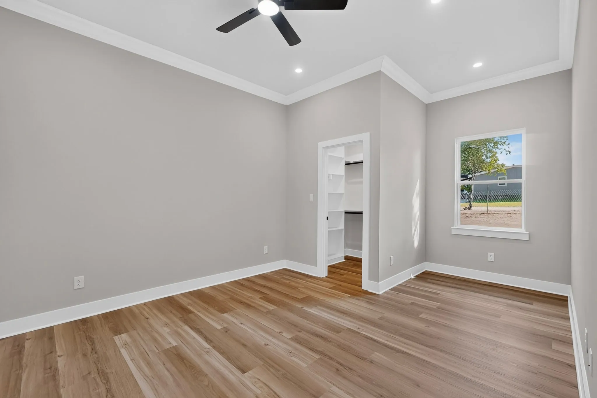 Recessed lighting, crown molding, a ceiling fan, wood-finish flooring, and a built-in closet with shelving