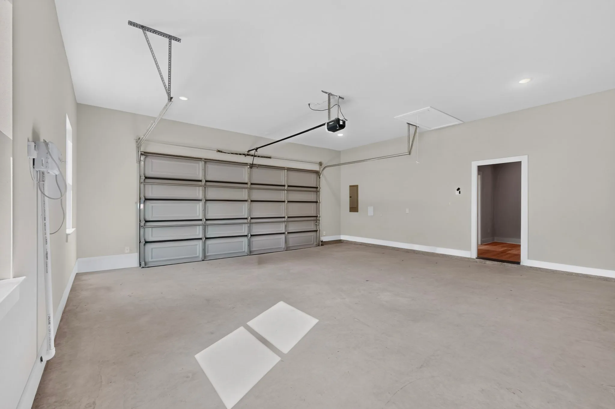 Spacious garage with an overhead door, smooth concrete flooring, recessed ceiling lighting, and a painted interior