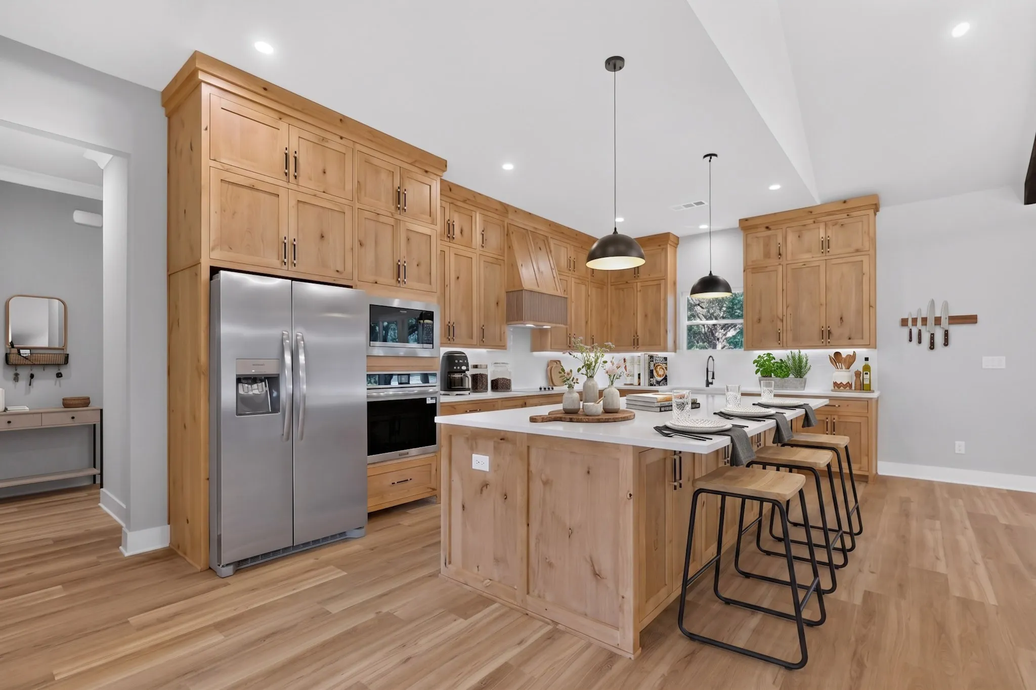 Kitchen featuring wood-finish cabinetry, stainless steel appliances, a center island with seating, pendant lighting, and wood-finish flooring