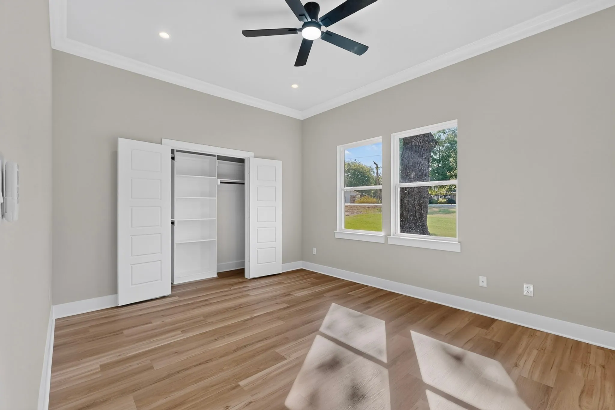 Wood-finish flooring with white trim, a ceiling fan, recessed lighting, and a bi-fold closet with built-in shelving