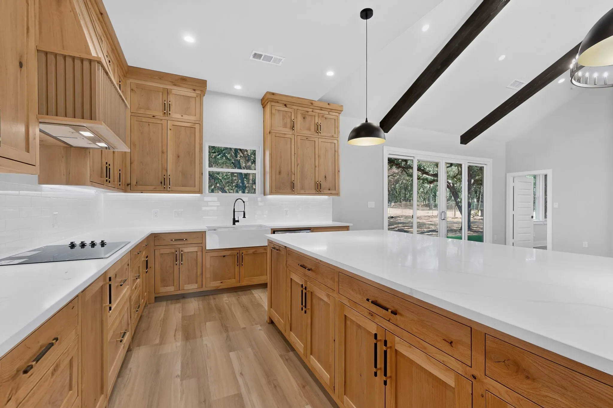Kitchen featuring light wood cabinetry, white countertops, a large center island, and vaulted ceilings with exposed beams