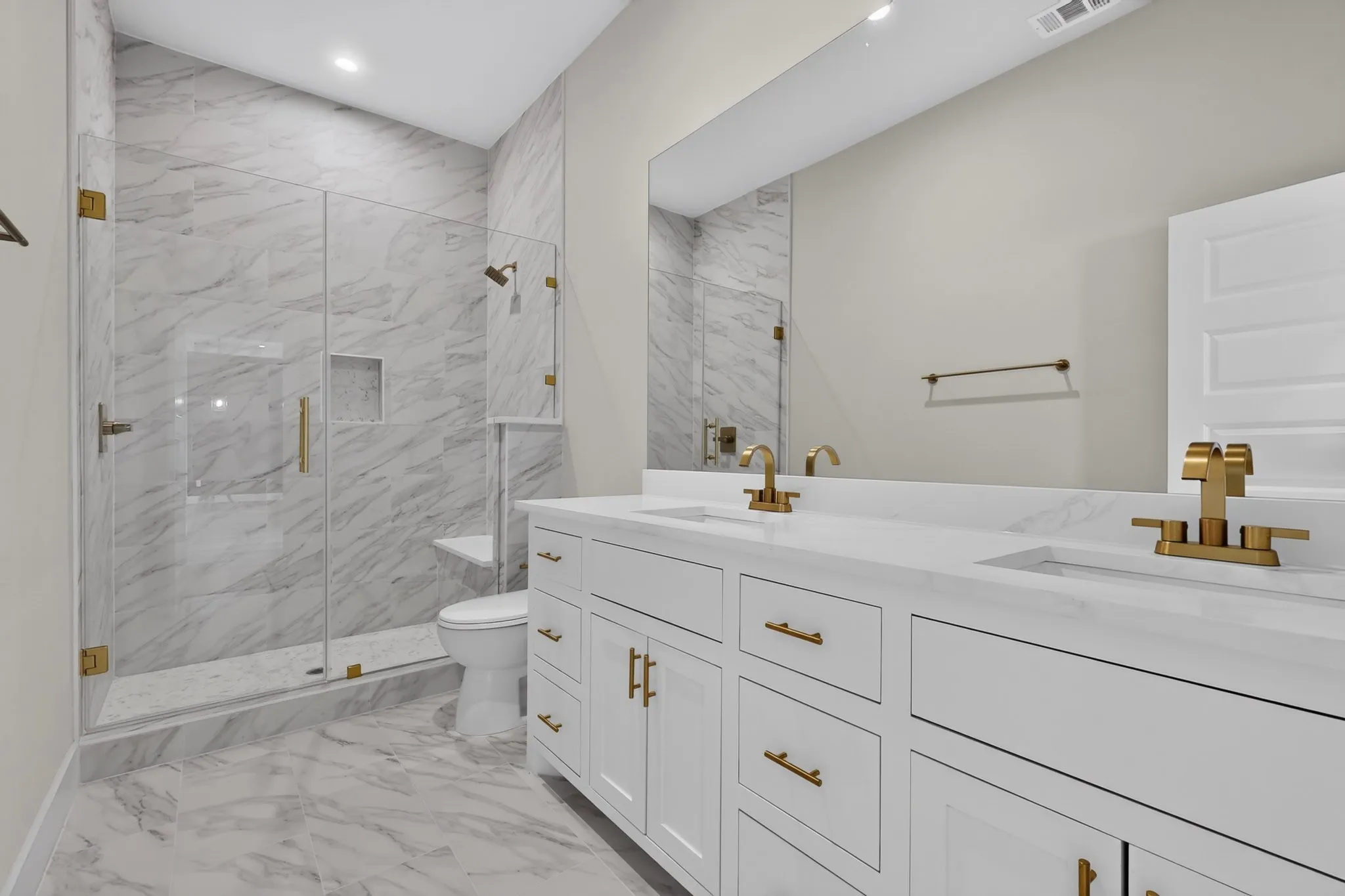 Dual vanity with white cabinetry, gold-tone hardware, and integrated sinks