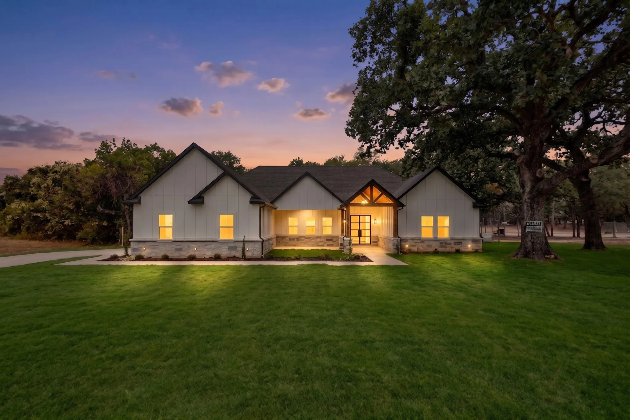 Contemporary farmhouse exterior with board and batten siding, stone veneer accents, and a dark shingle roof