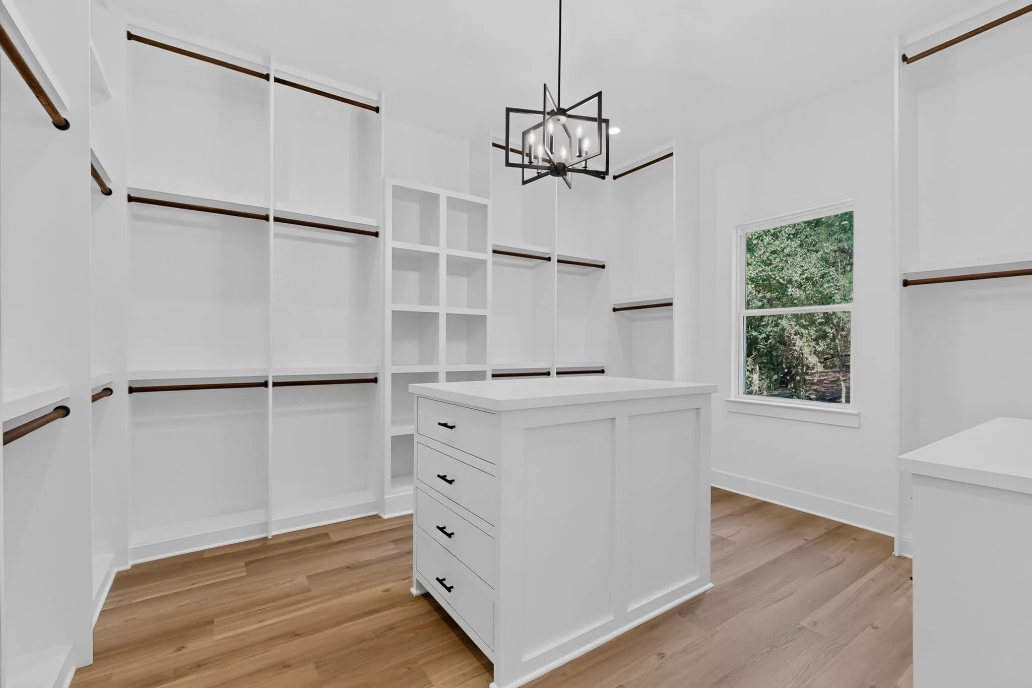 Custom closet system with built-in shelving, wood-finish flooring, and a central storage island with​​‌​​​​‌​​‌‌​‌‌​​​‌‌​‌​‌​‌​​​‌​​ drawers