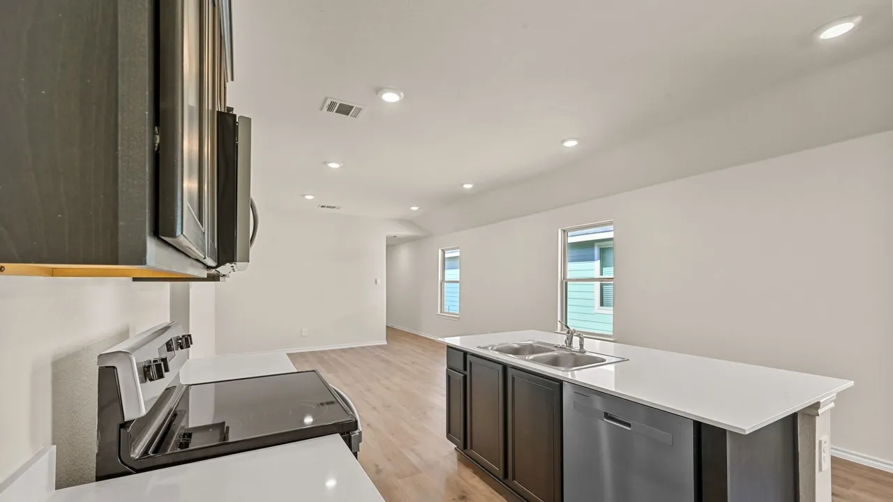 Open concept kitchen featuring stainless steel appliances, recessed lighting, an island with a double basin sink, and wood-finish flooring