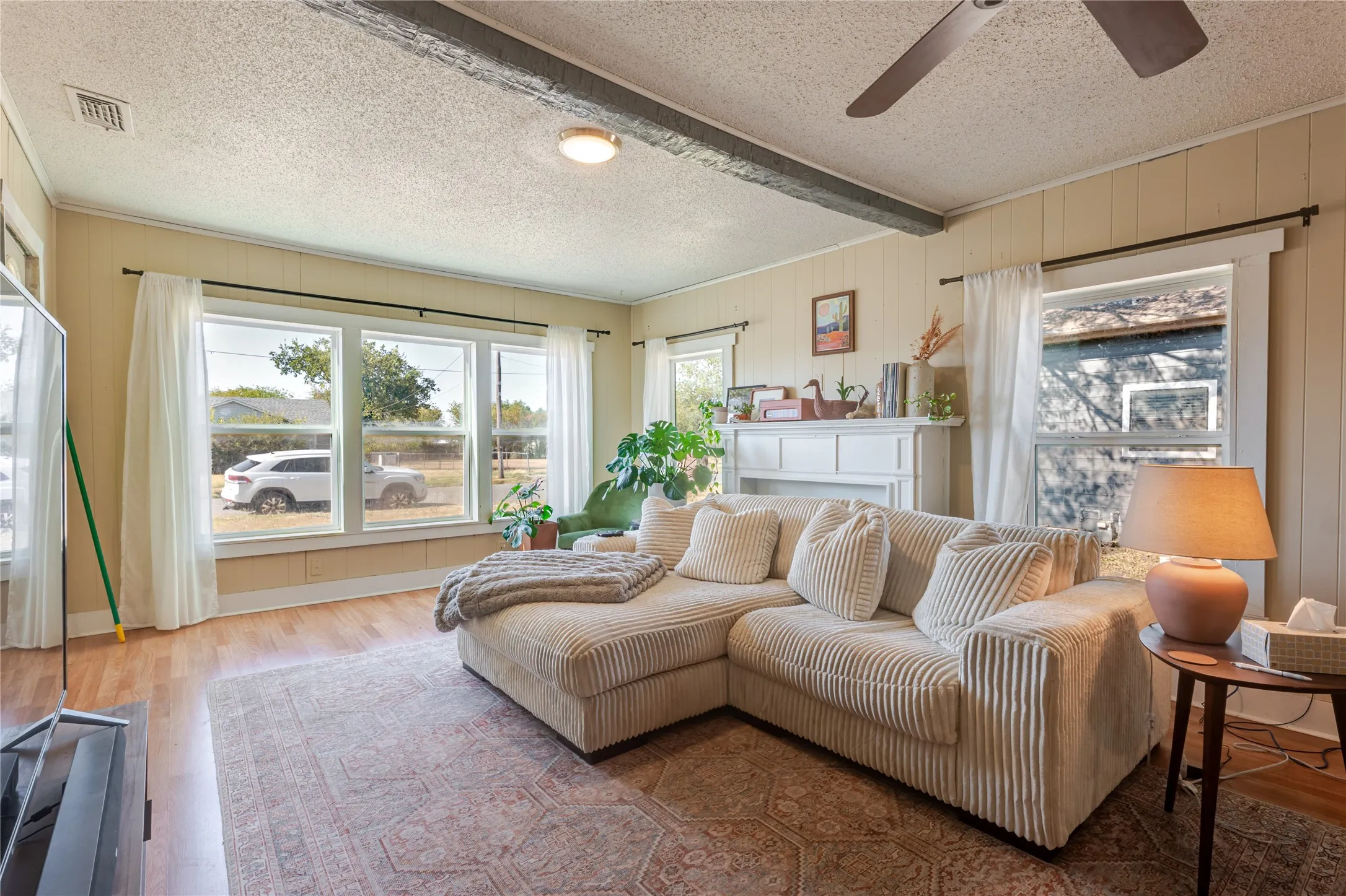 Living area featuring wood-finish flooring, a ceiling fan with integrated lighting, and white trim details