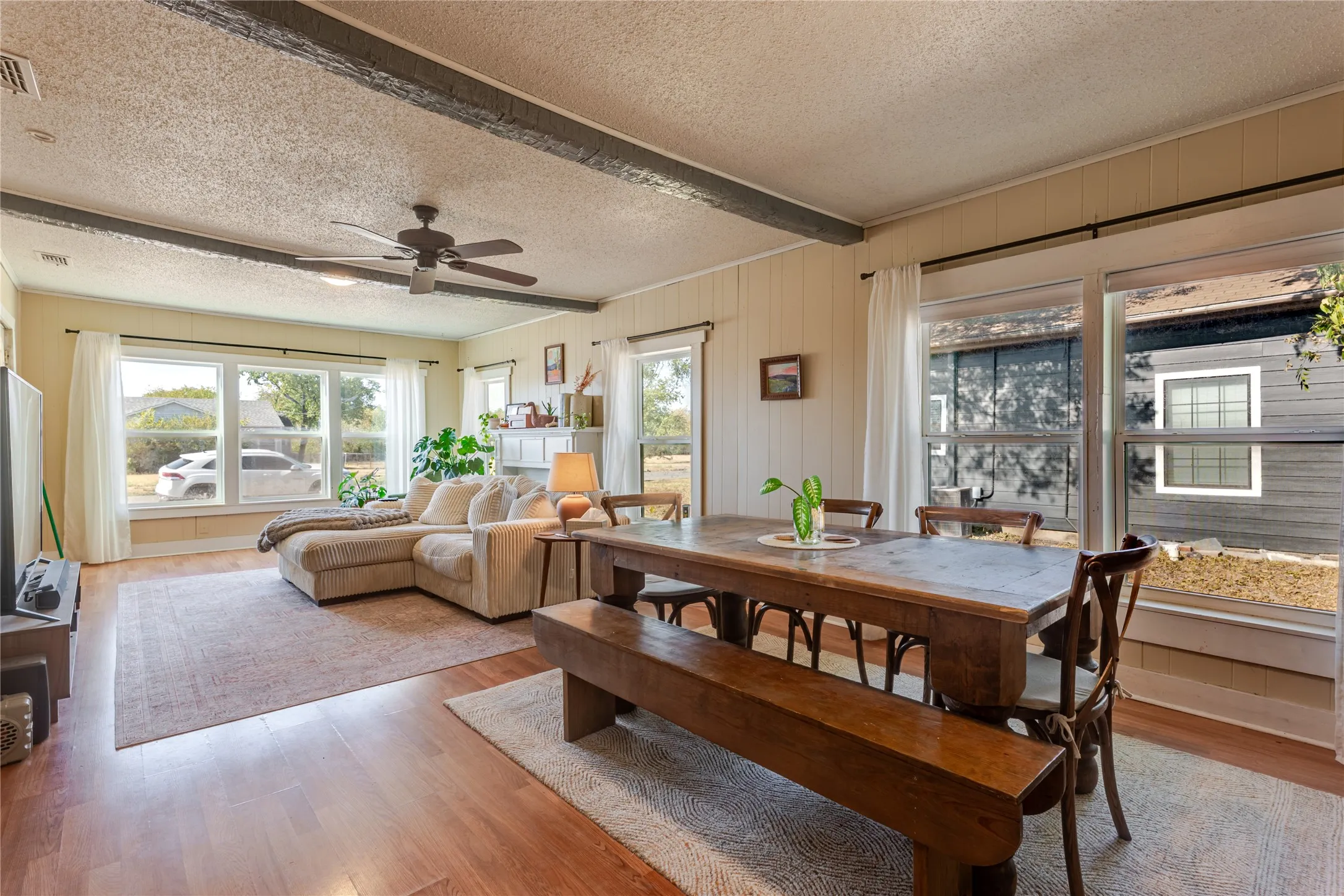 Wood-finish flooring throughout, exposed ceiling beams, and a ceiling fan with integrated lighting