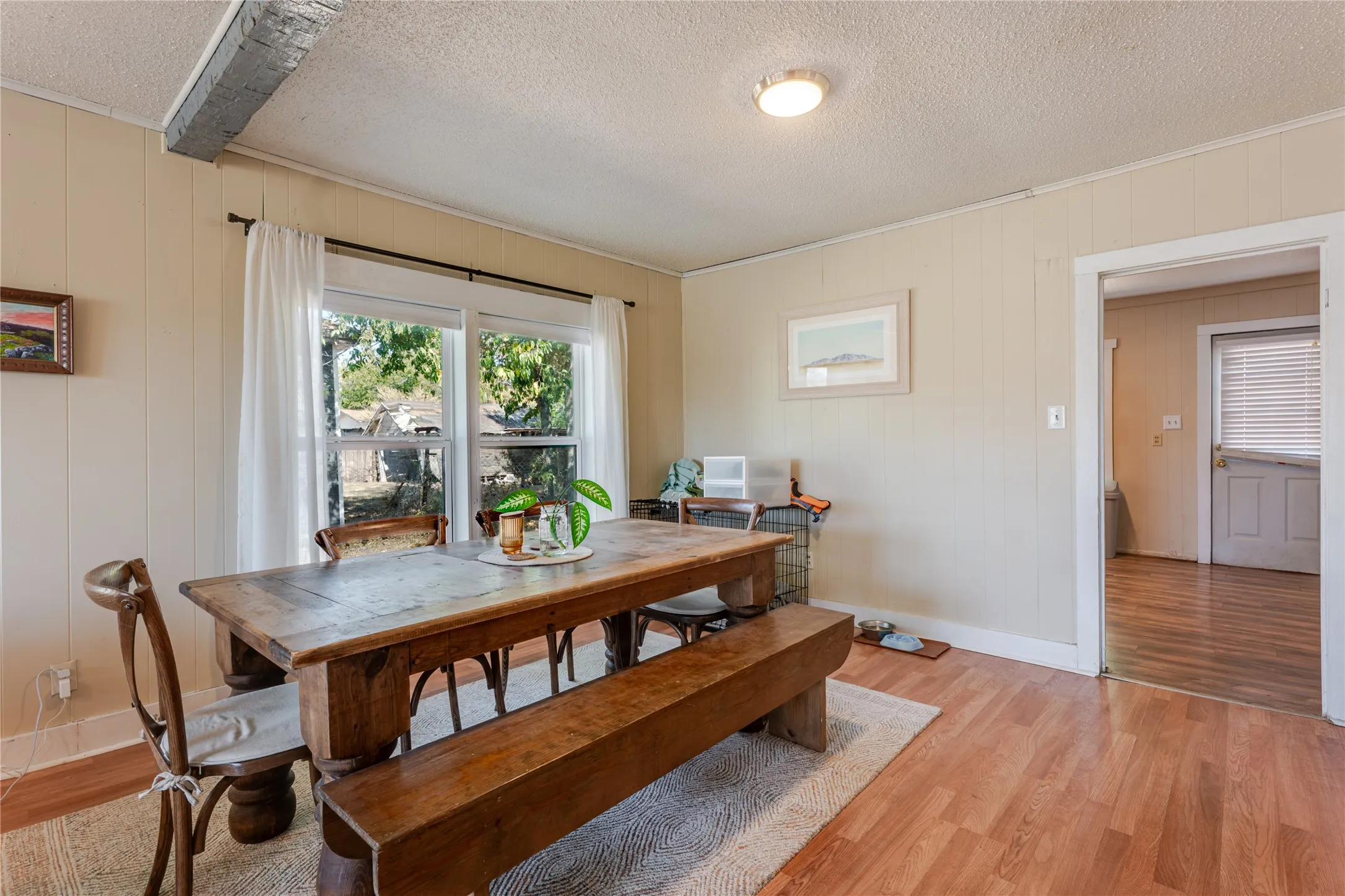 Wood-finish flooring with a ceiling-mounted light fixture, and a window with white trim