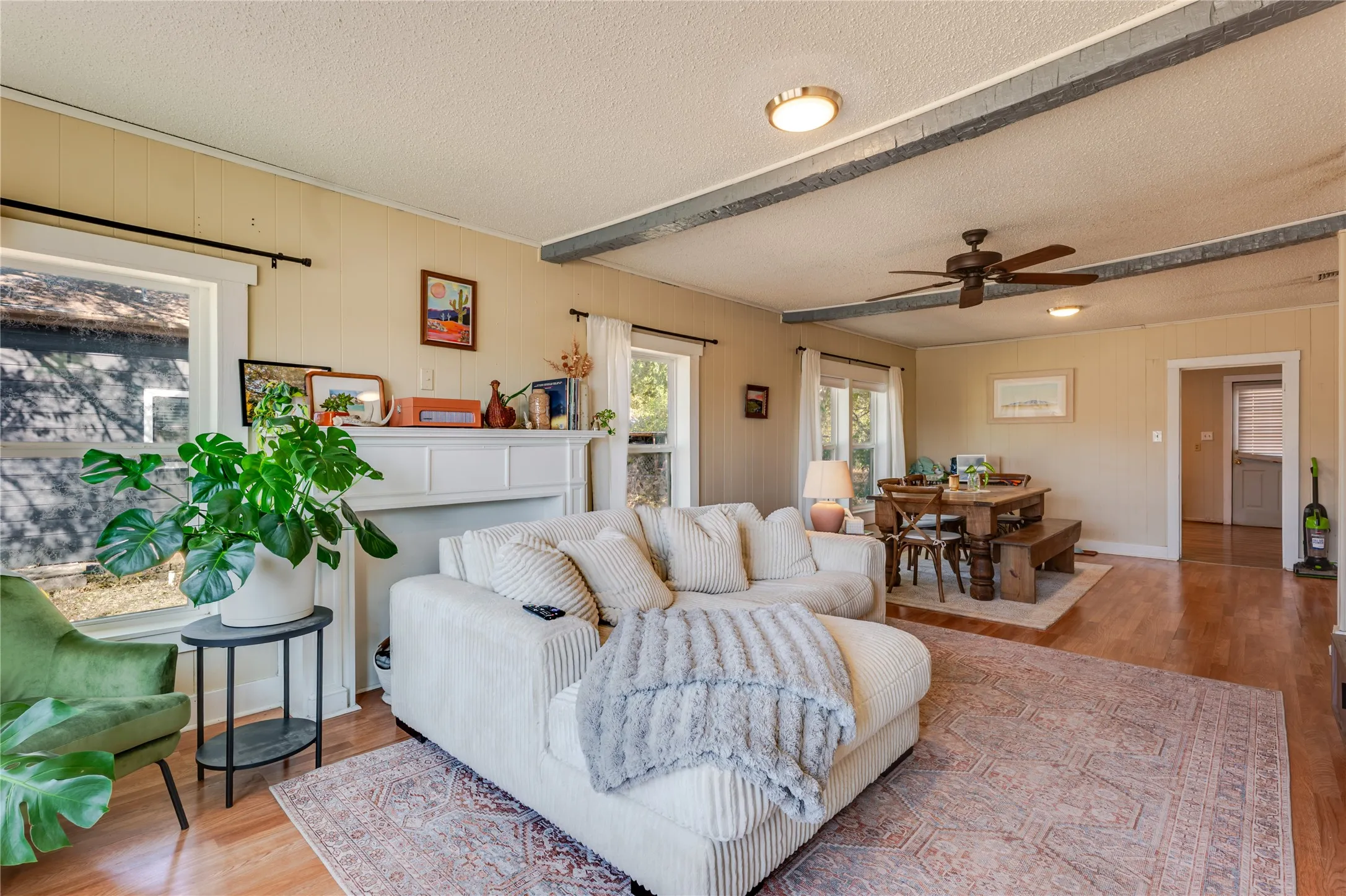 Wood-finish flooring, exposed ceiling beams, recessed lighting, ceiling fan, and white window trim