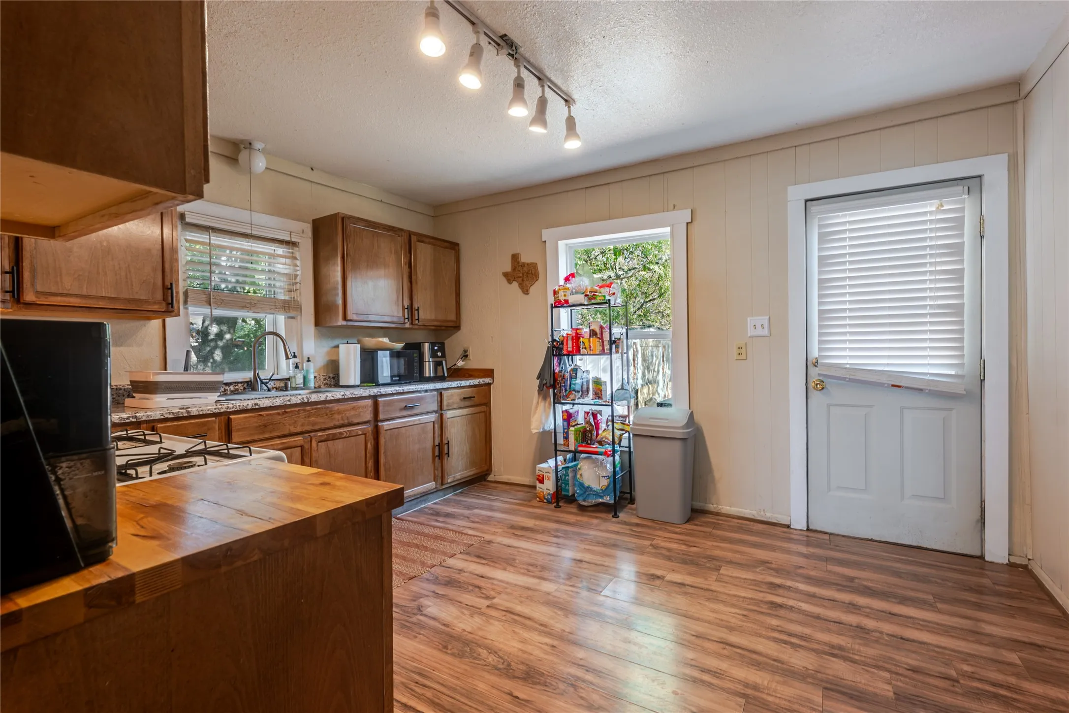 Kitchen featuring wood-finish flooring, wood cabinetry, track lighting, and a built-in sink