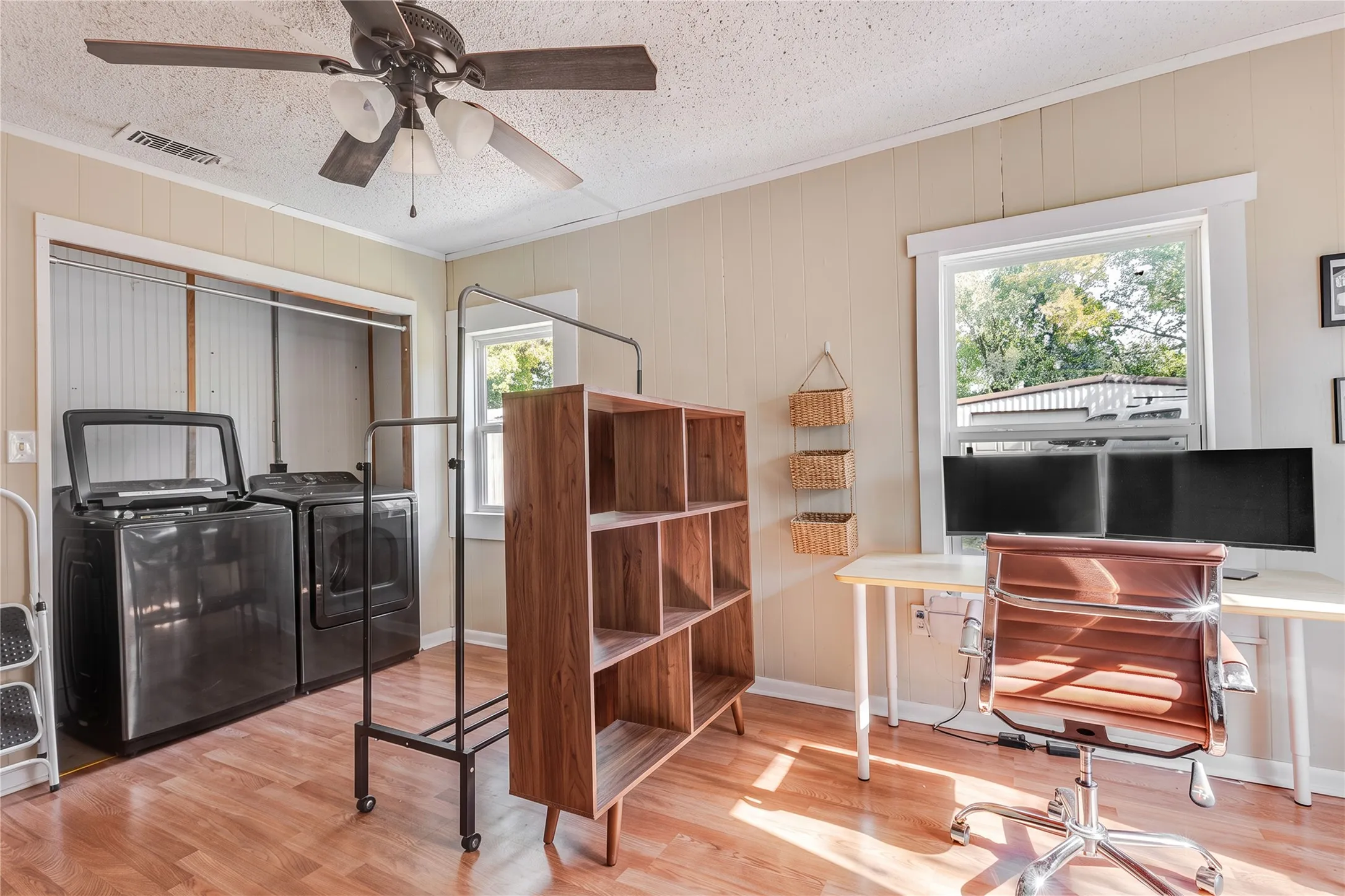 Laundry area with dual appliance hookups, wood-finish flooring, and natural light from a window