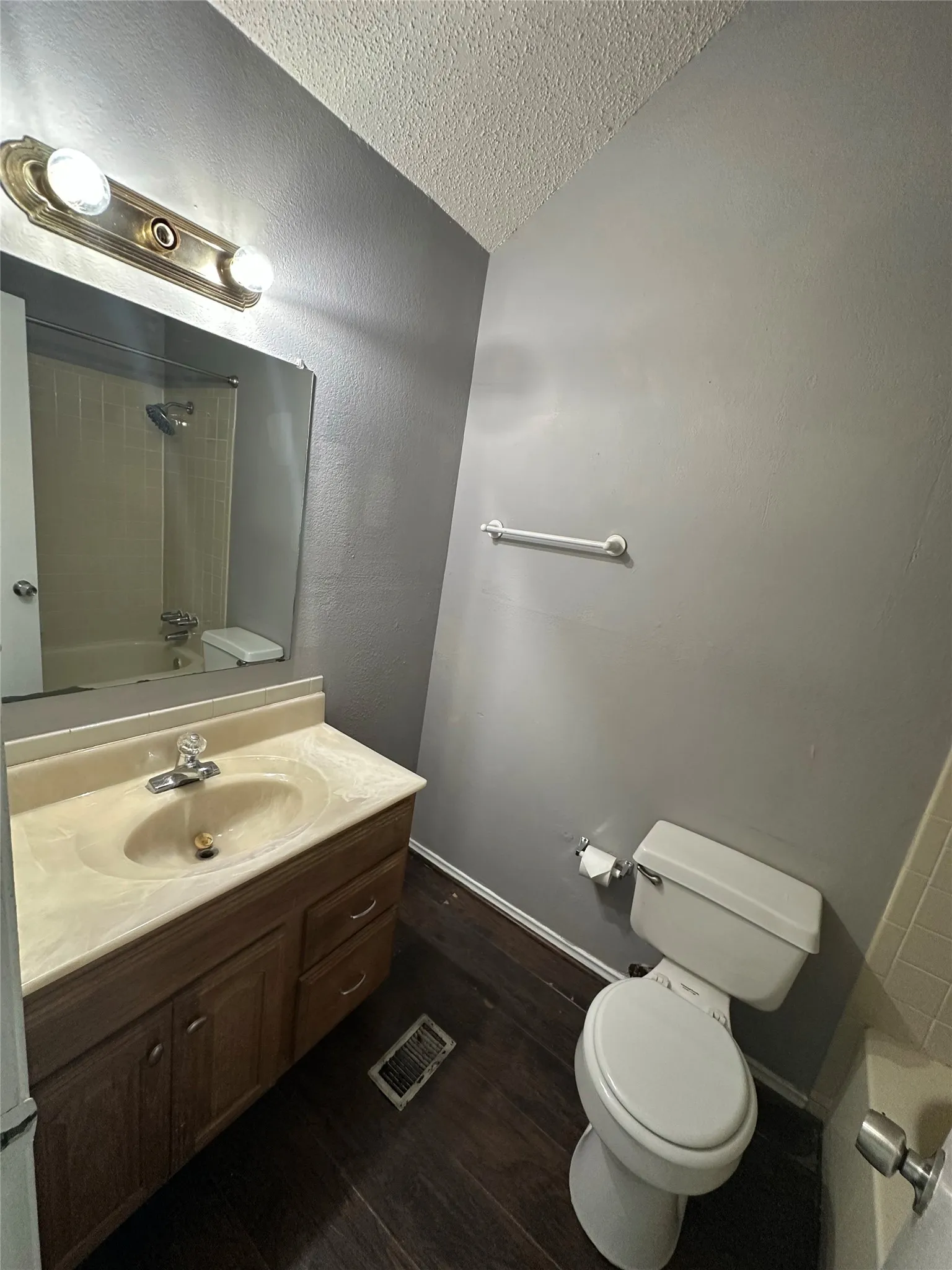 Bathroom featuring a vanity with an integrated sink, wood-finish flooring, a toilet, and a shower-tub combination