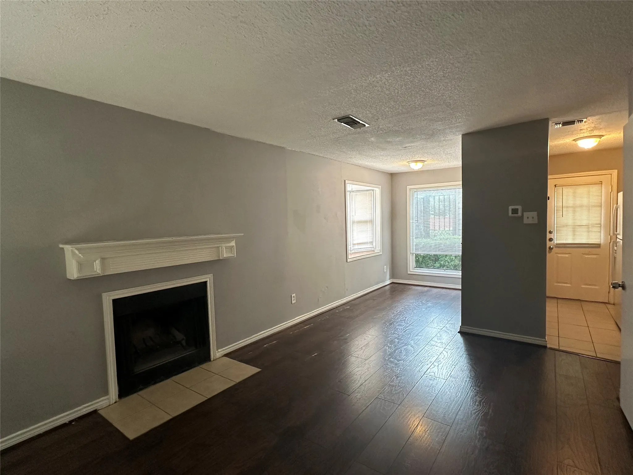 Fireplace with a white mantel, wood-finish flooring, and neutral wall paint