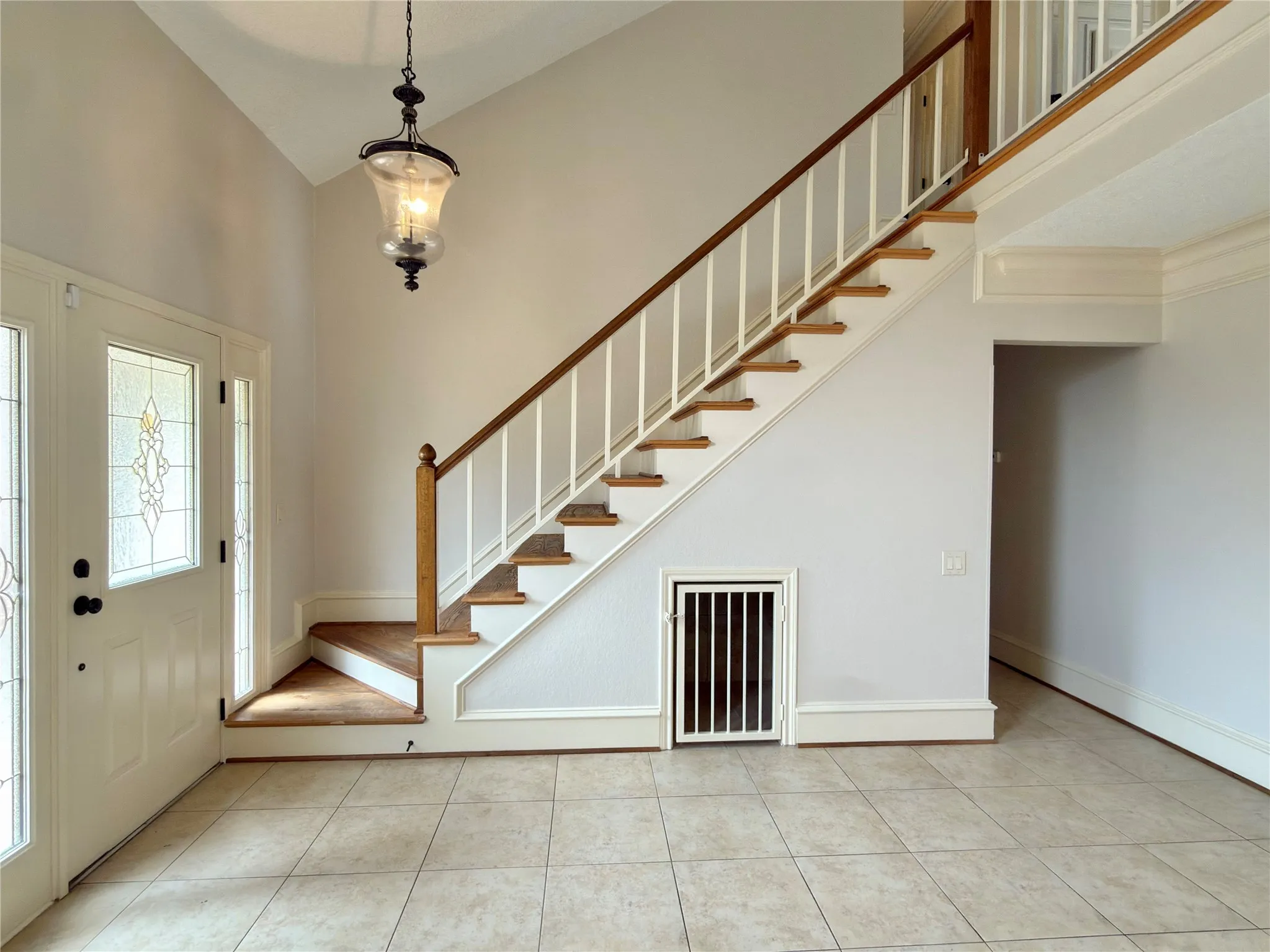 Two-story foyer featuring a tile floor, wood staircase with white balusters, and a decorative glass entry door with sidelights
