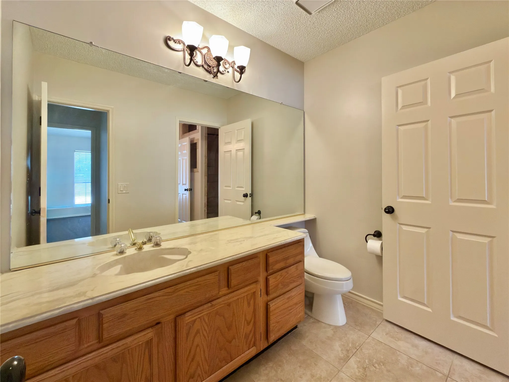 Vanity with a single undermount sink, a light-toned countertop, and wood-finish cabinetry