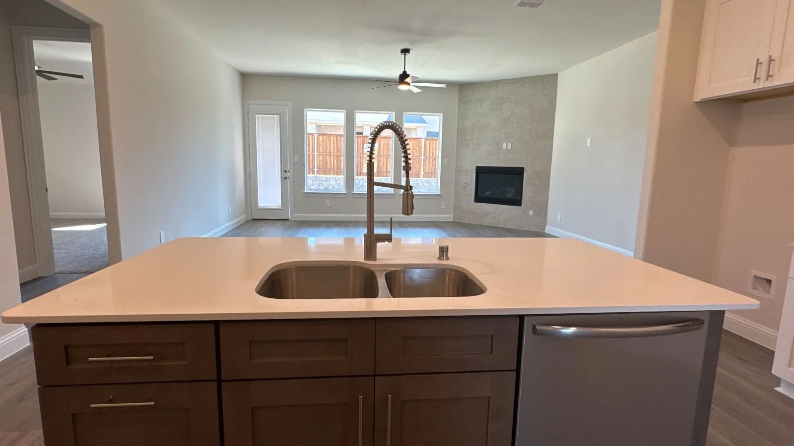 Kitchen island with an undermount dual-basin sink, gooseneck faucet, integrated dishwasher, and light-toned countertop