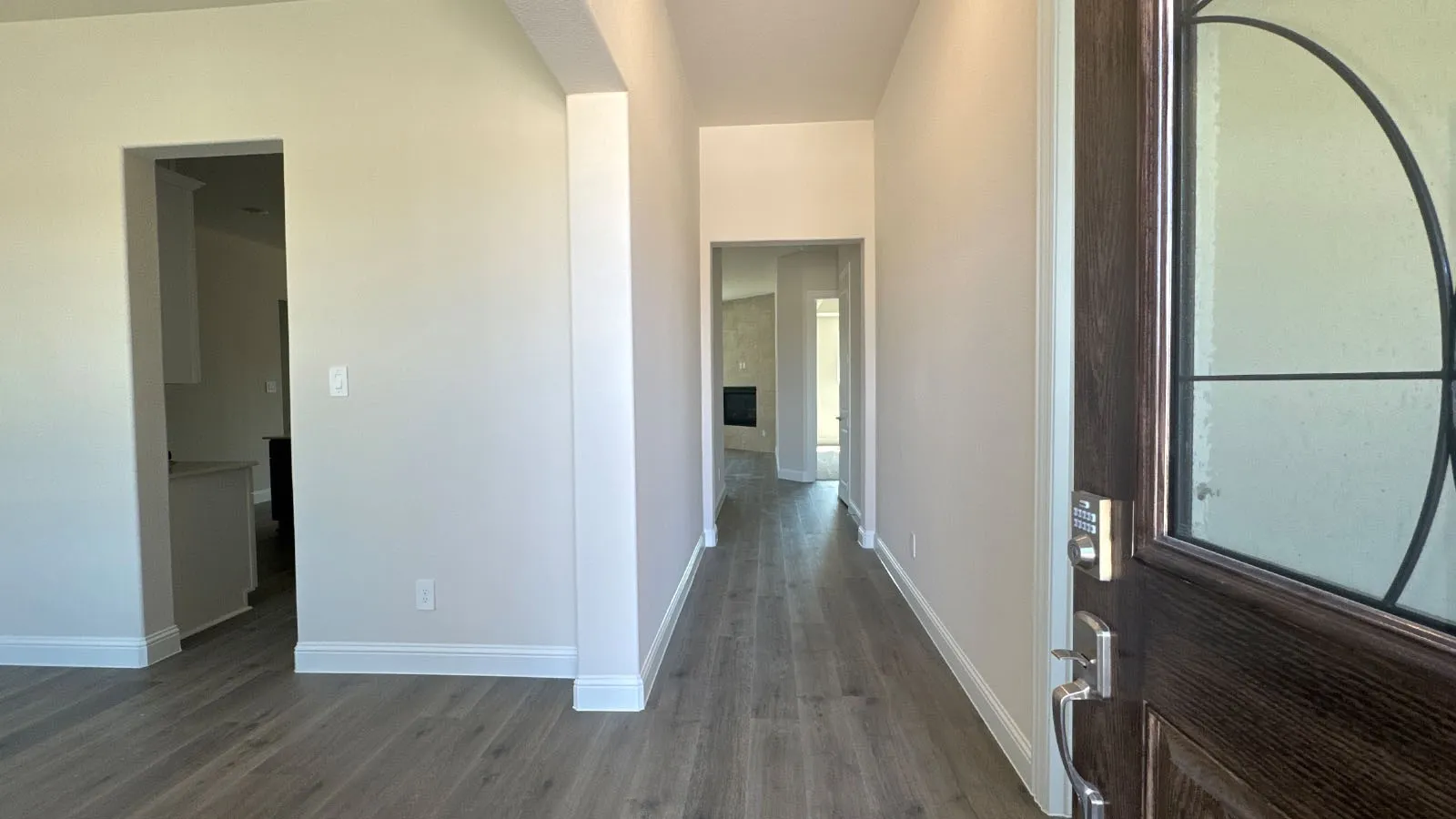 Entryway featuring wood-finish flooring, white trim, and a dark wood door with decorative glass inlay and brushed nickel hardware