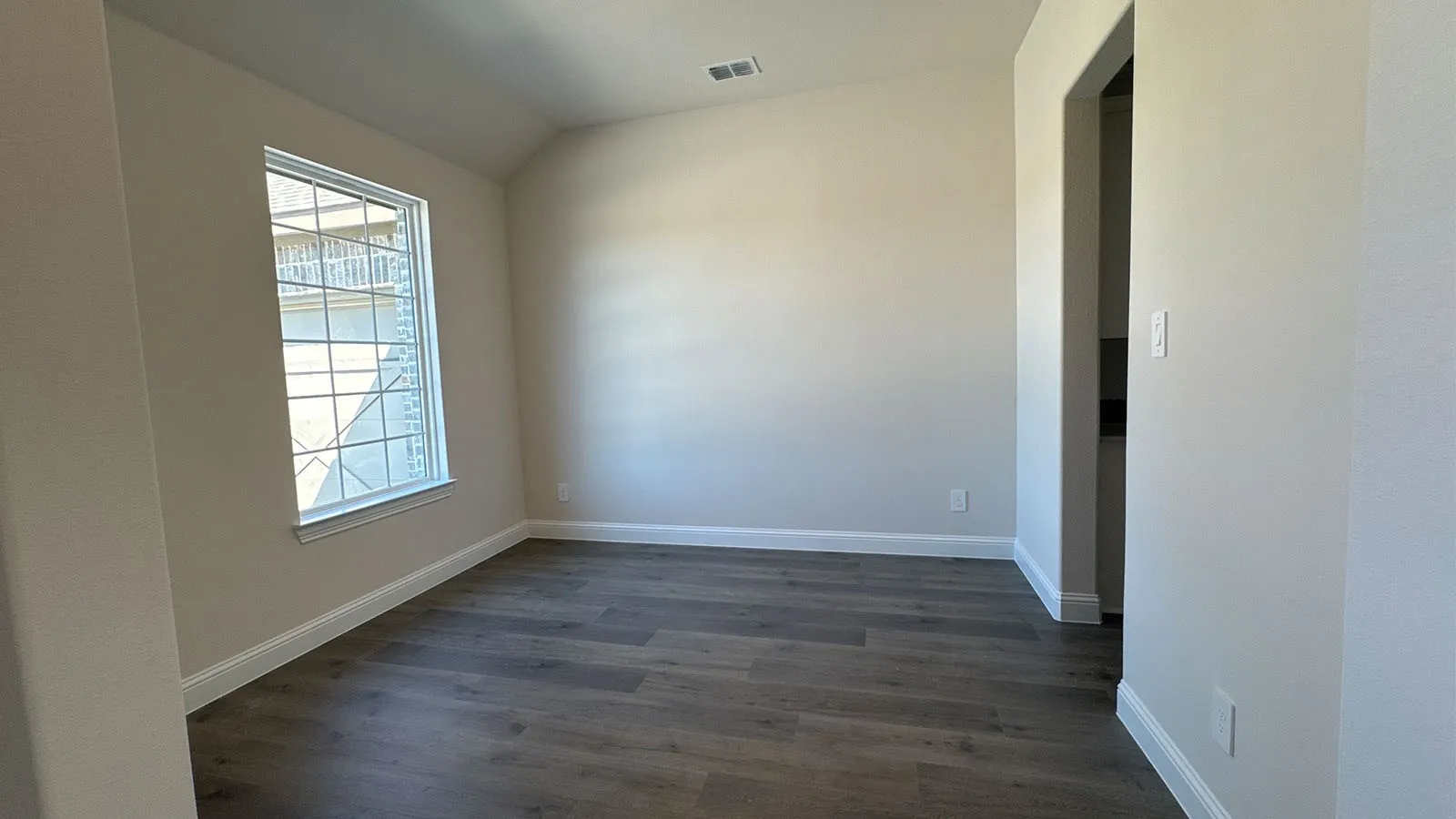 Spacious room featuring wood-finish flooring and a single-pane window