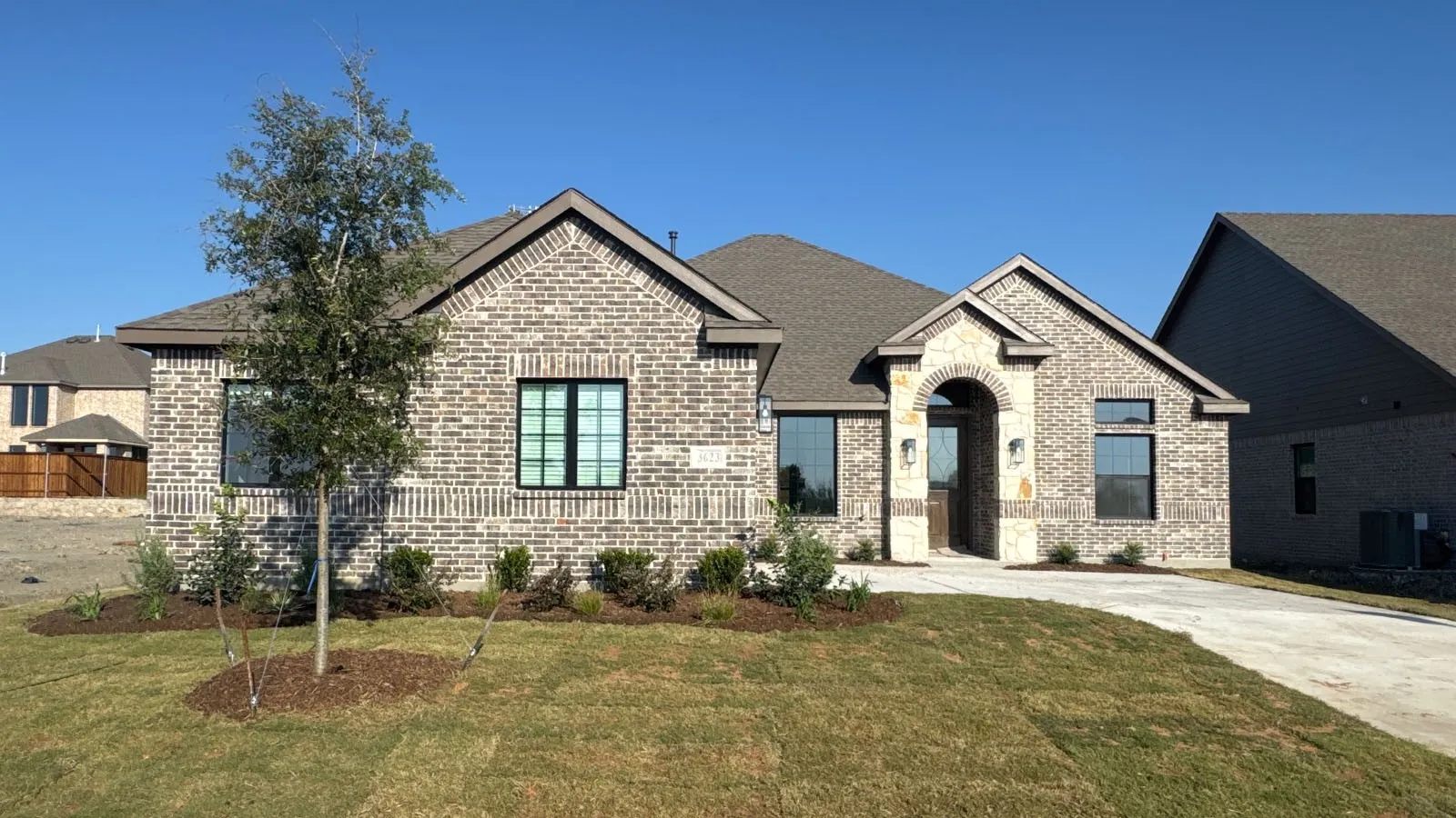 Brick and stone exterior with a gabled roofline, arched entryway, and dark-framed windows