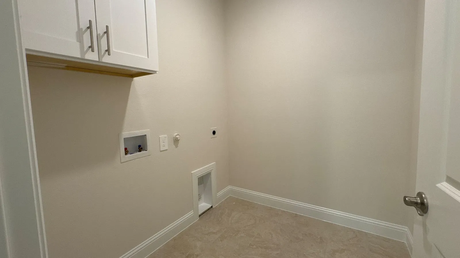 White shaker-style cabinetry with brushed nickel hardware, light-toned wall paint, tiled flooring, and white trim
