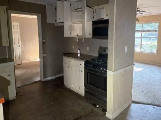 Kitchen featuring white cabinetry, dark countertops, a black range, and an over-the-range microwave