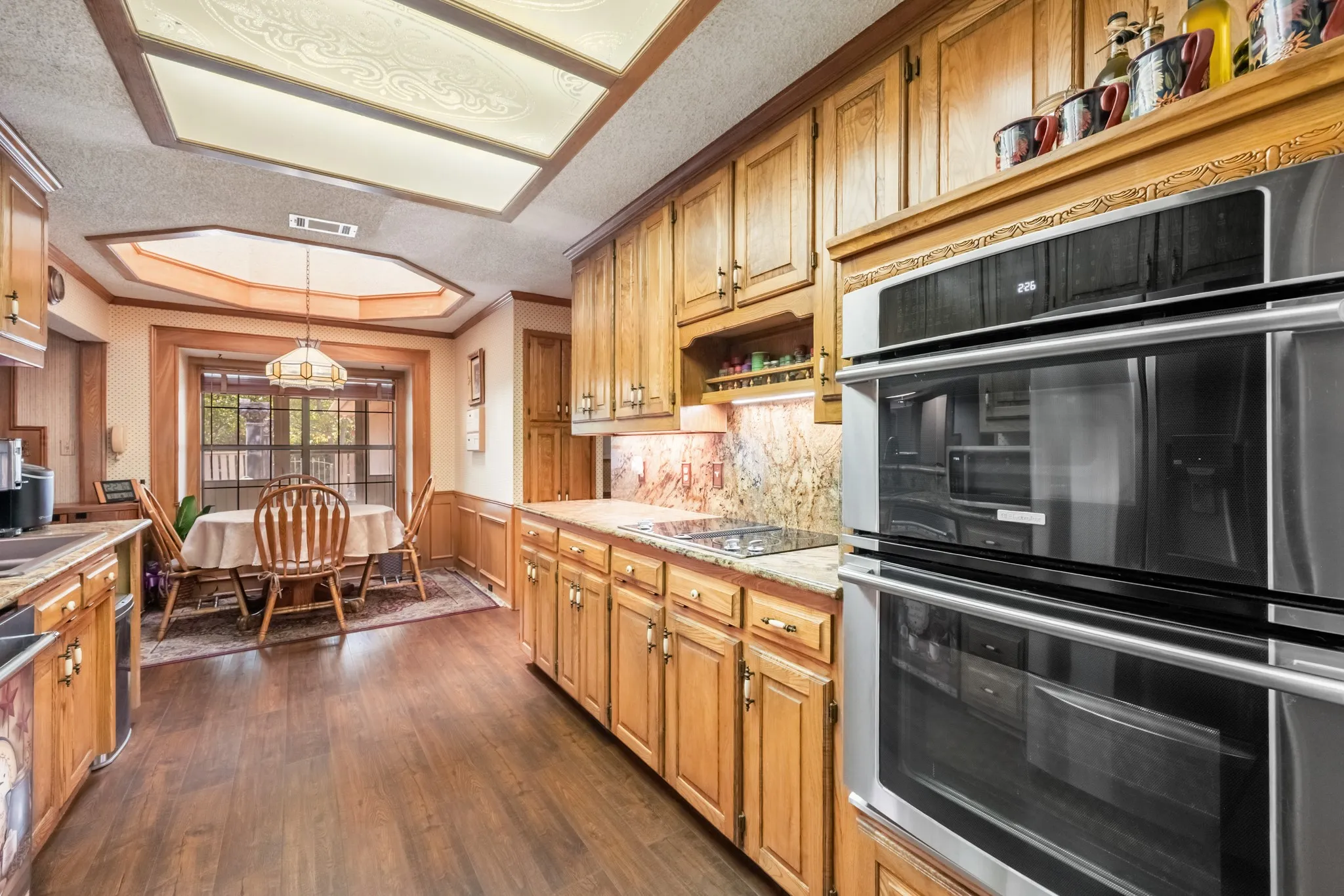 Kitchen featuring wood-finish flooring, recessed lighting, double wall ovens, granite countertops, and wood cabinetry