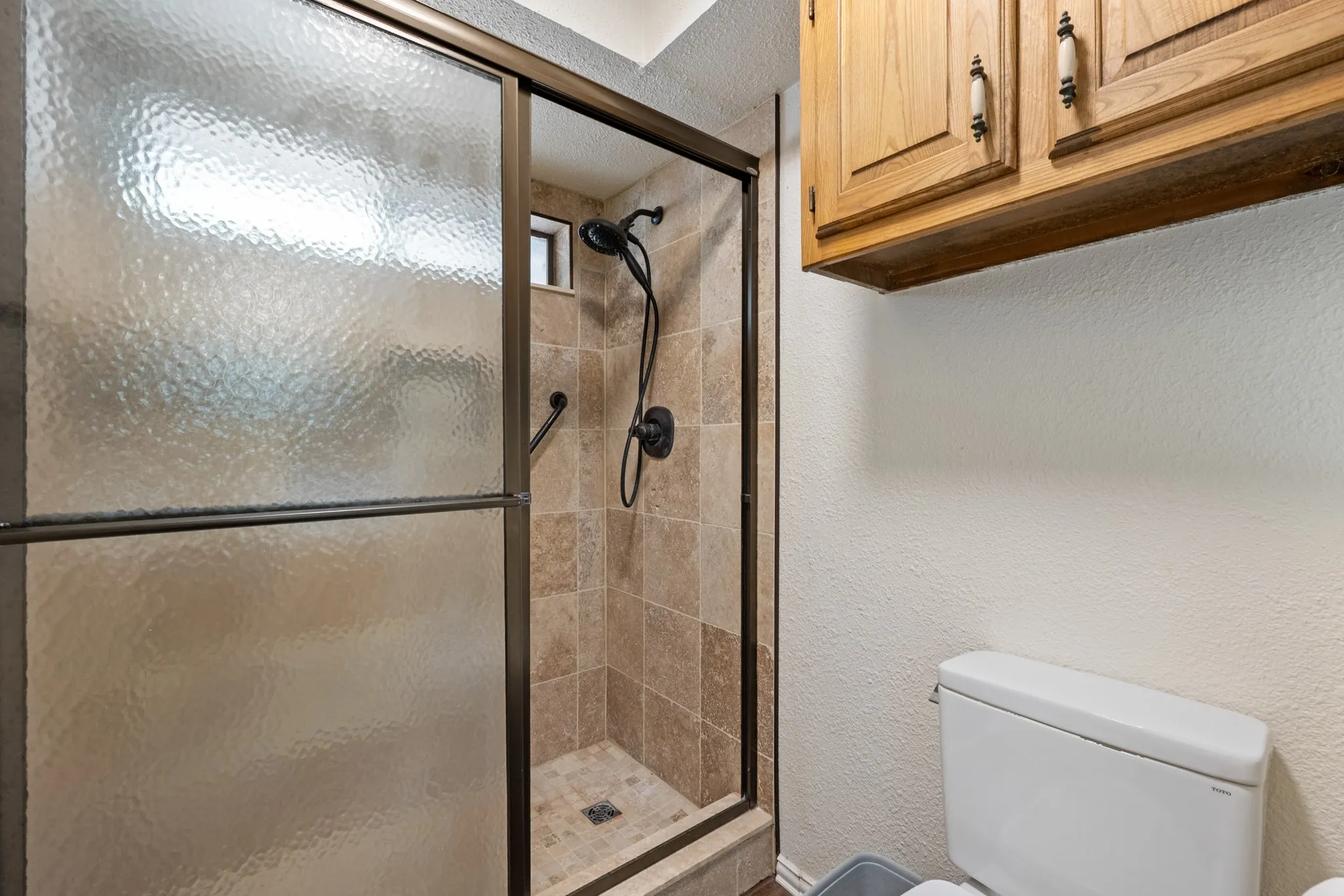 Tiled shower enclosure with a bronze-finish frame and fixtures