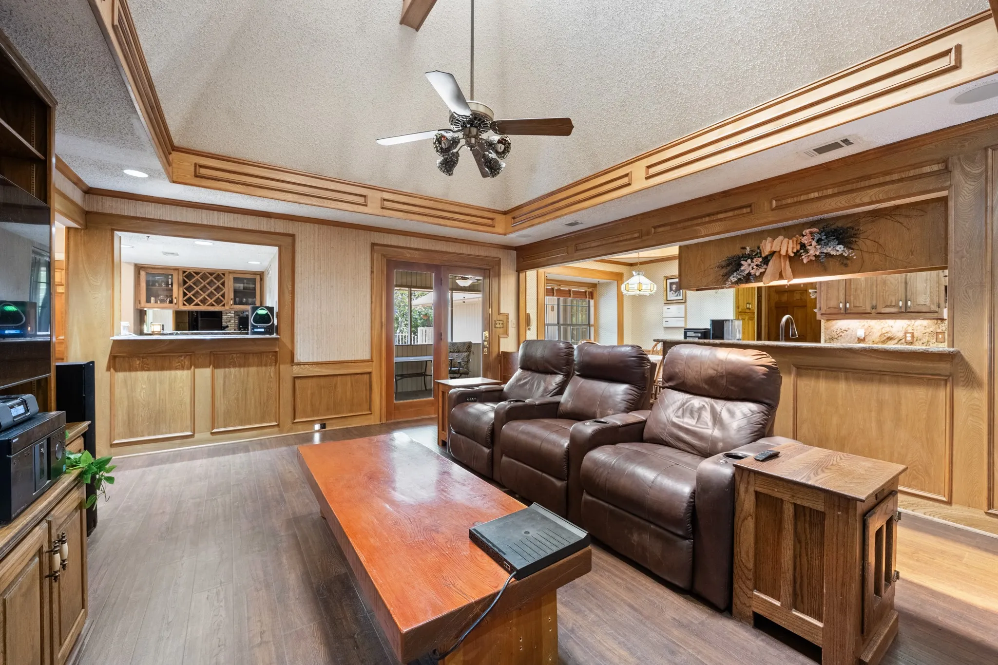Vaulted ceiling with wood trim, wood-finish flooring, built-in wet bar, and sliding glass doors