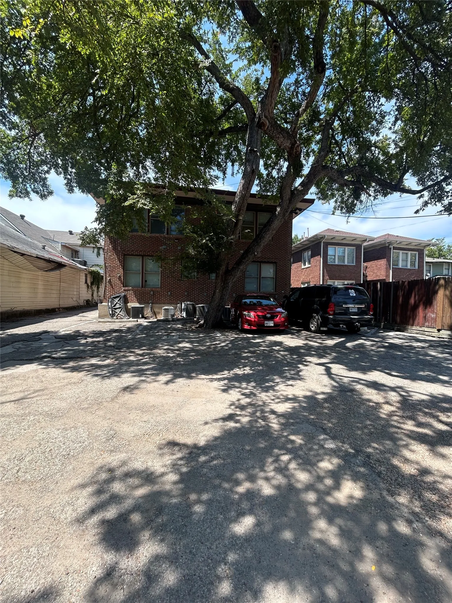 Brick exterior building with multiple windows, complemented by a mature tree providing natural shade
