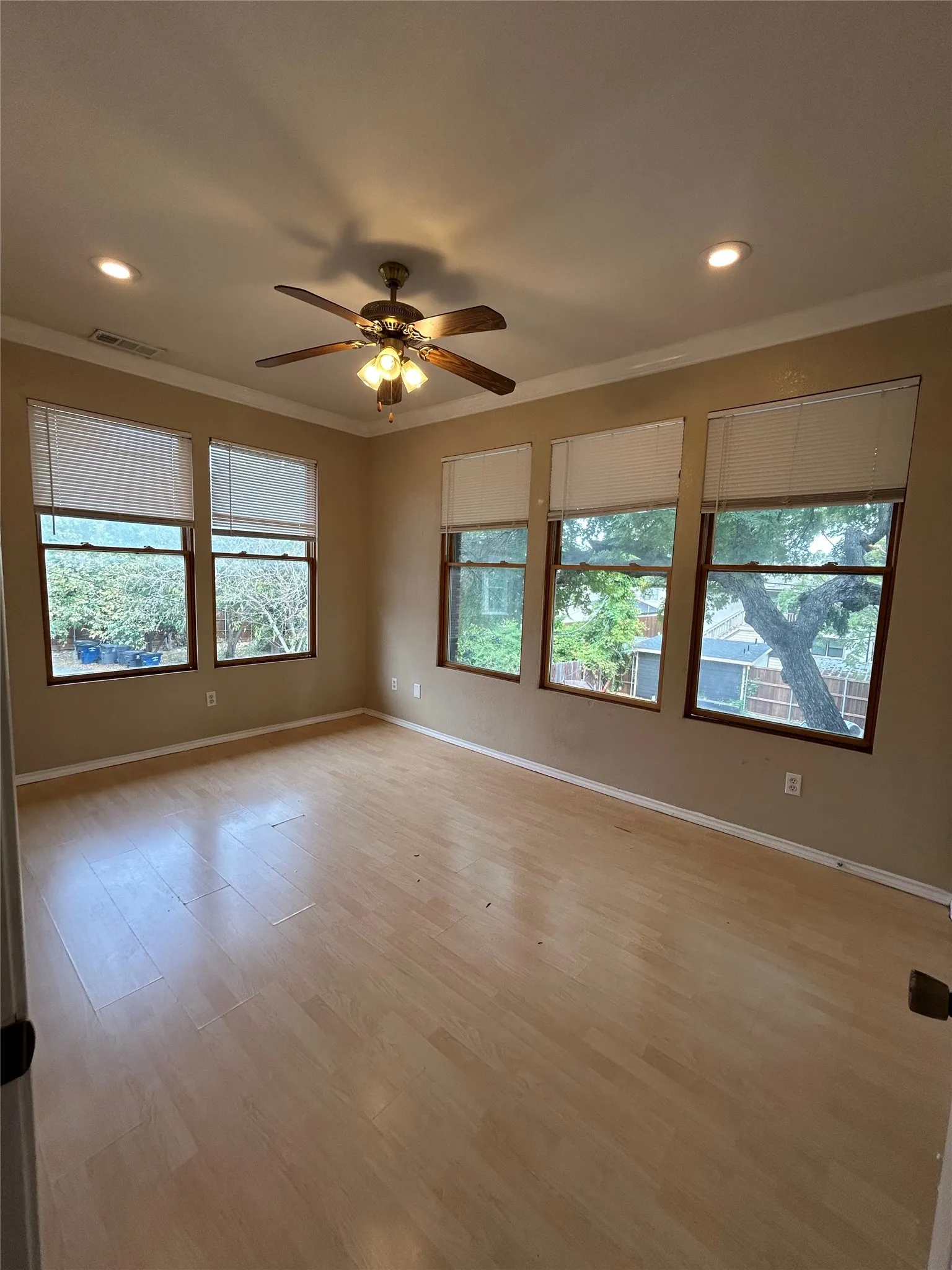 Expansive room featuring wood-finish flooring, crown molding, and recessed lighting
