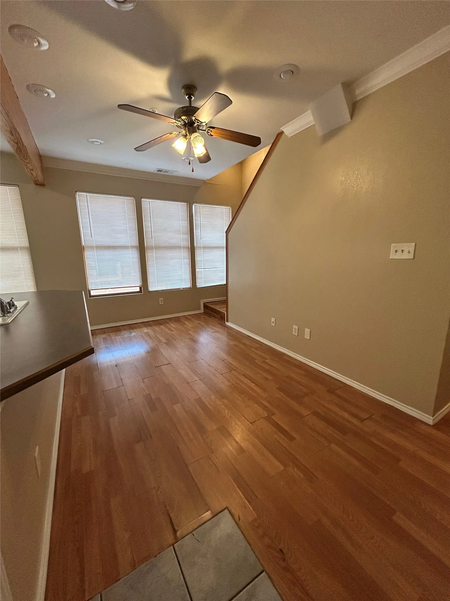 Wood-finish flooring, recessed lighting, ceiling fan, crown molding, and multiple windows