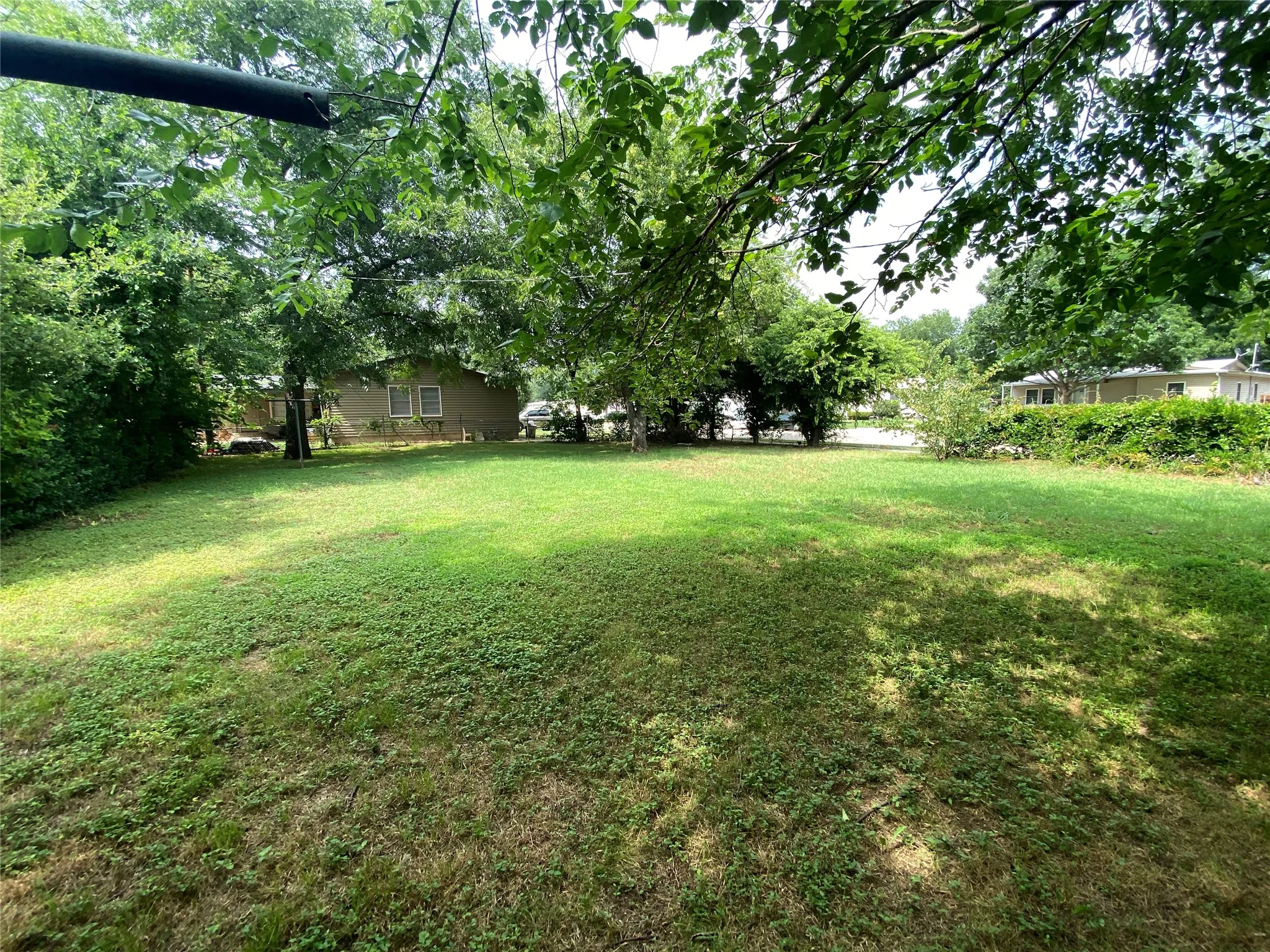 Expansive grassy yard with mature trees providing partial shade