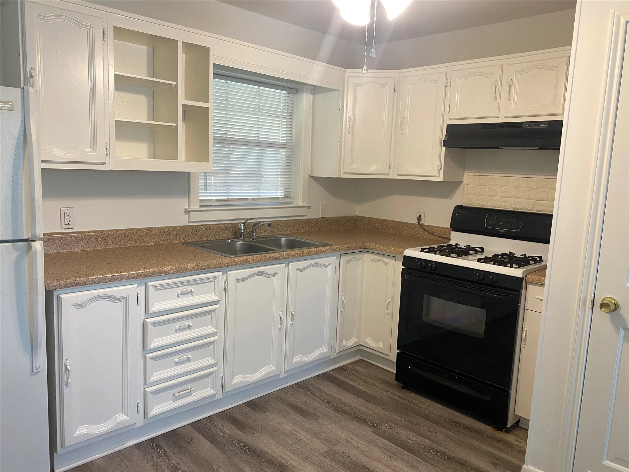 White cabinetry, dual basin stainless steel sink, gas range, integrated range hood, and wood-finish flooring