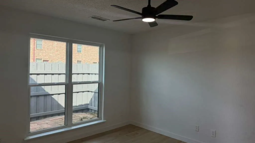 White walls with wood-finish flooring, a contemporary ceiling fan, and a double-pane window