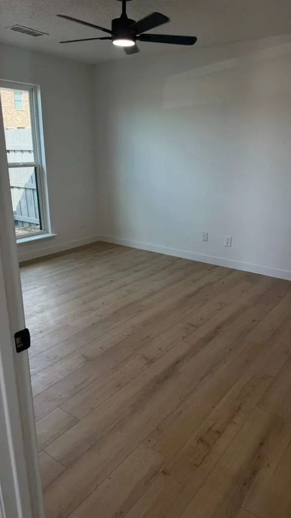 Wood-finish flooring, white walls, and a contemporary ceiling fan with integrated lighting