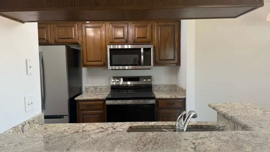 Kitchen featuring wood cabinetry, stainless steel appliances, and stone countertops