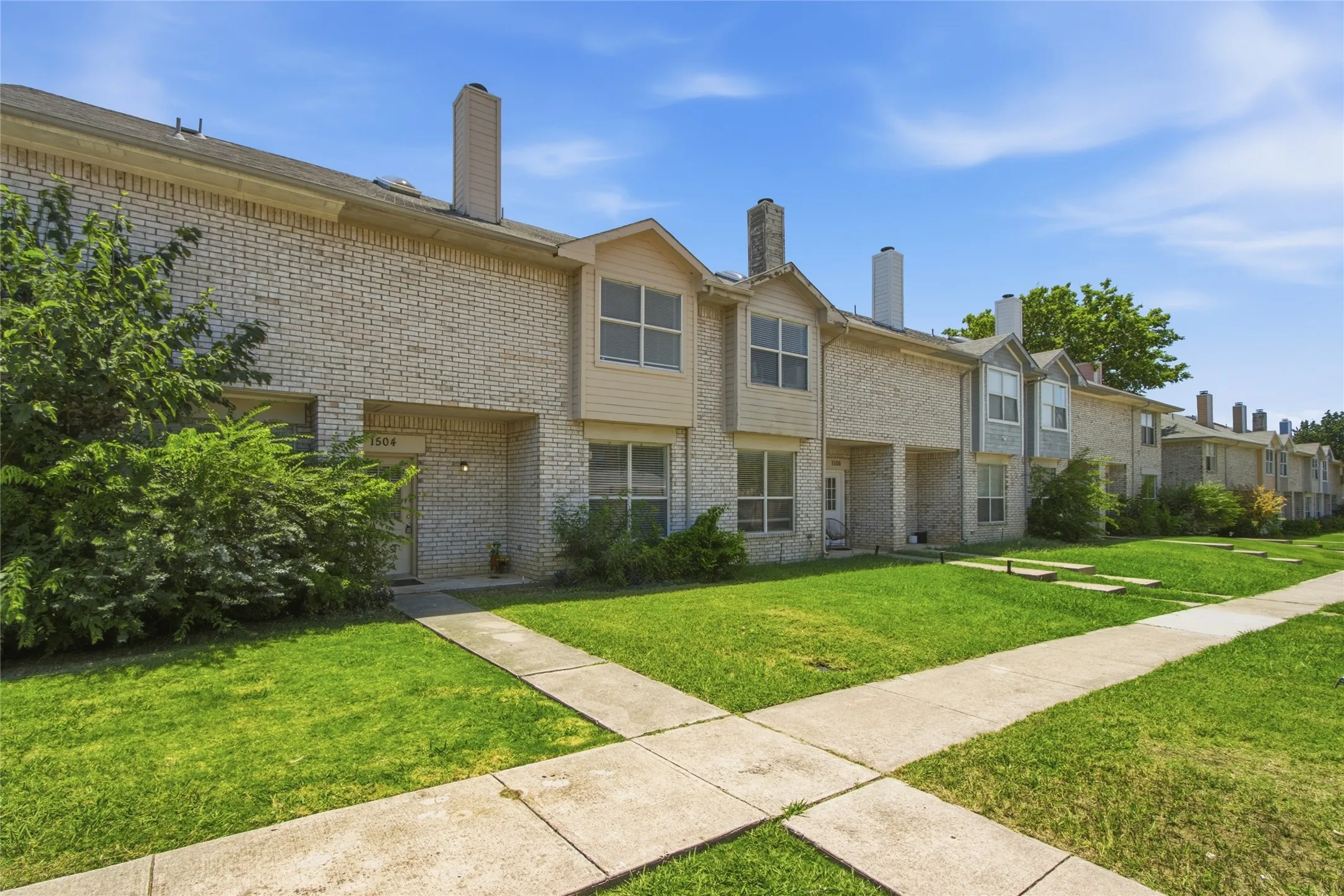 Row of townhomes featuring light brick facades and individual entryways