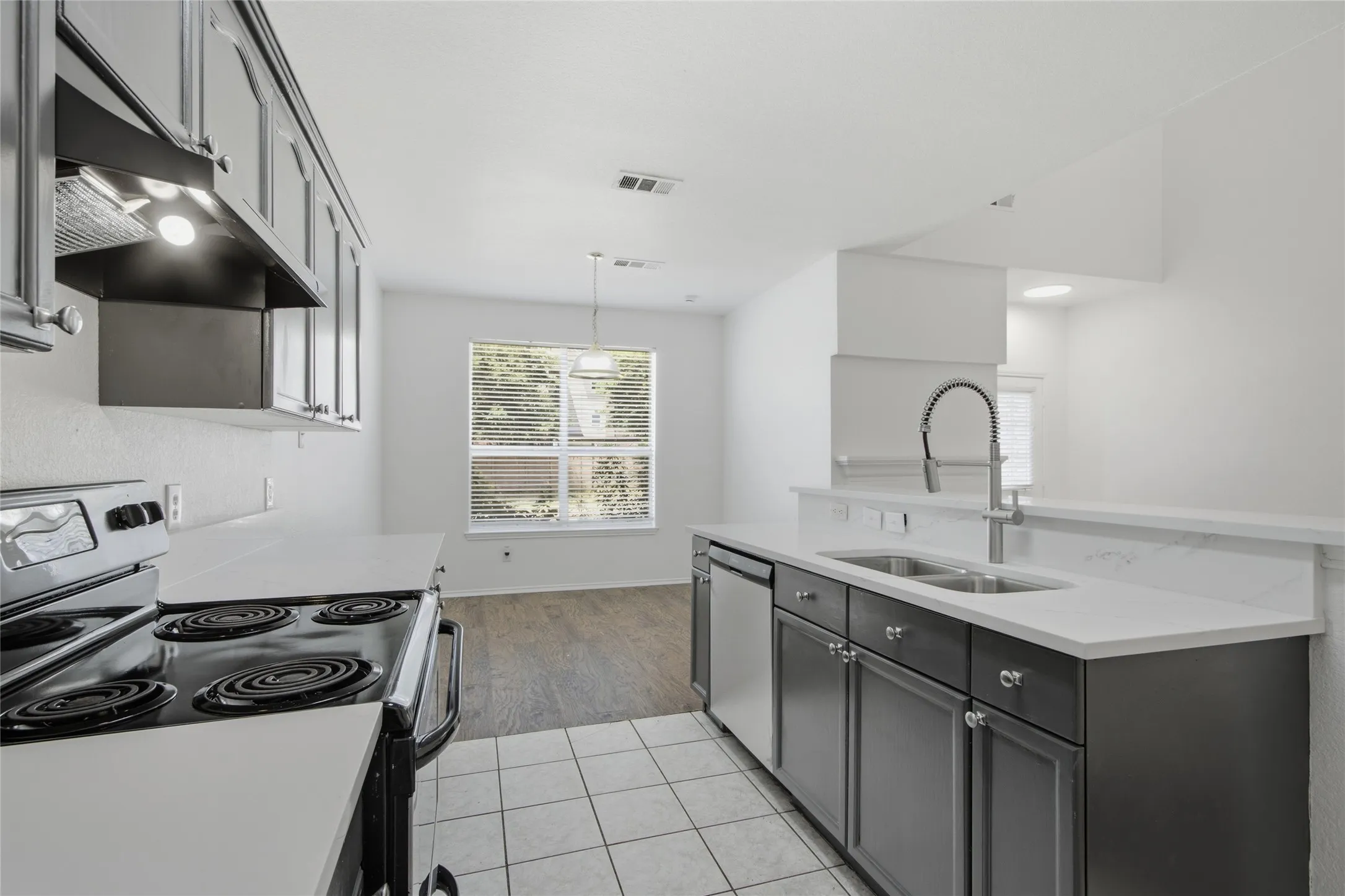 Modern kitchen featuring white countertops, stainless steel appliances, dark cabinetry, and tile flooring