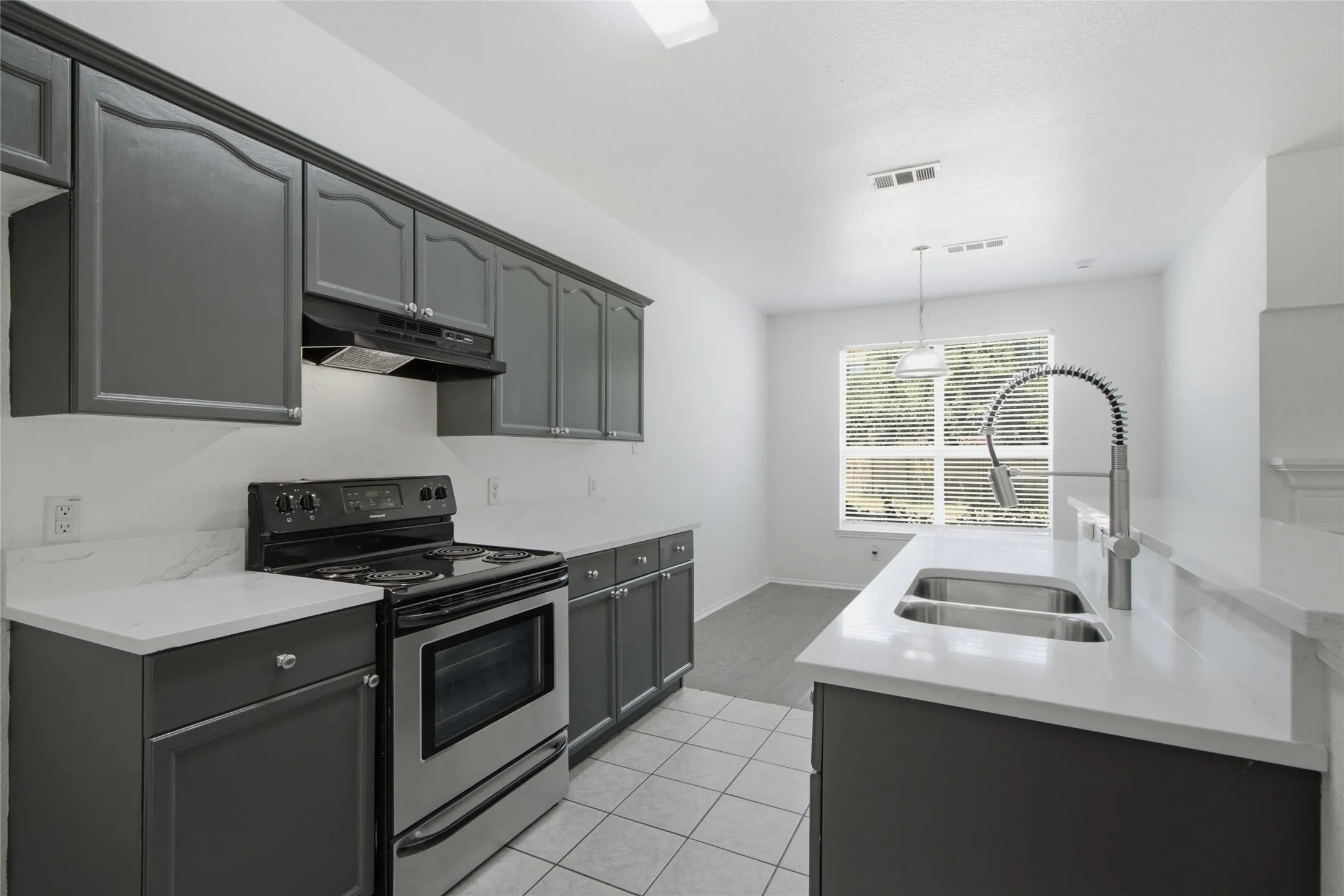 Contemporary kitchen featuring dark gray cabinetry, white countertops, and stainless steel appliances
