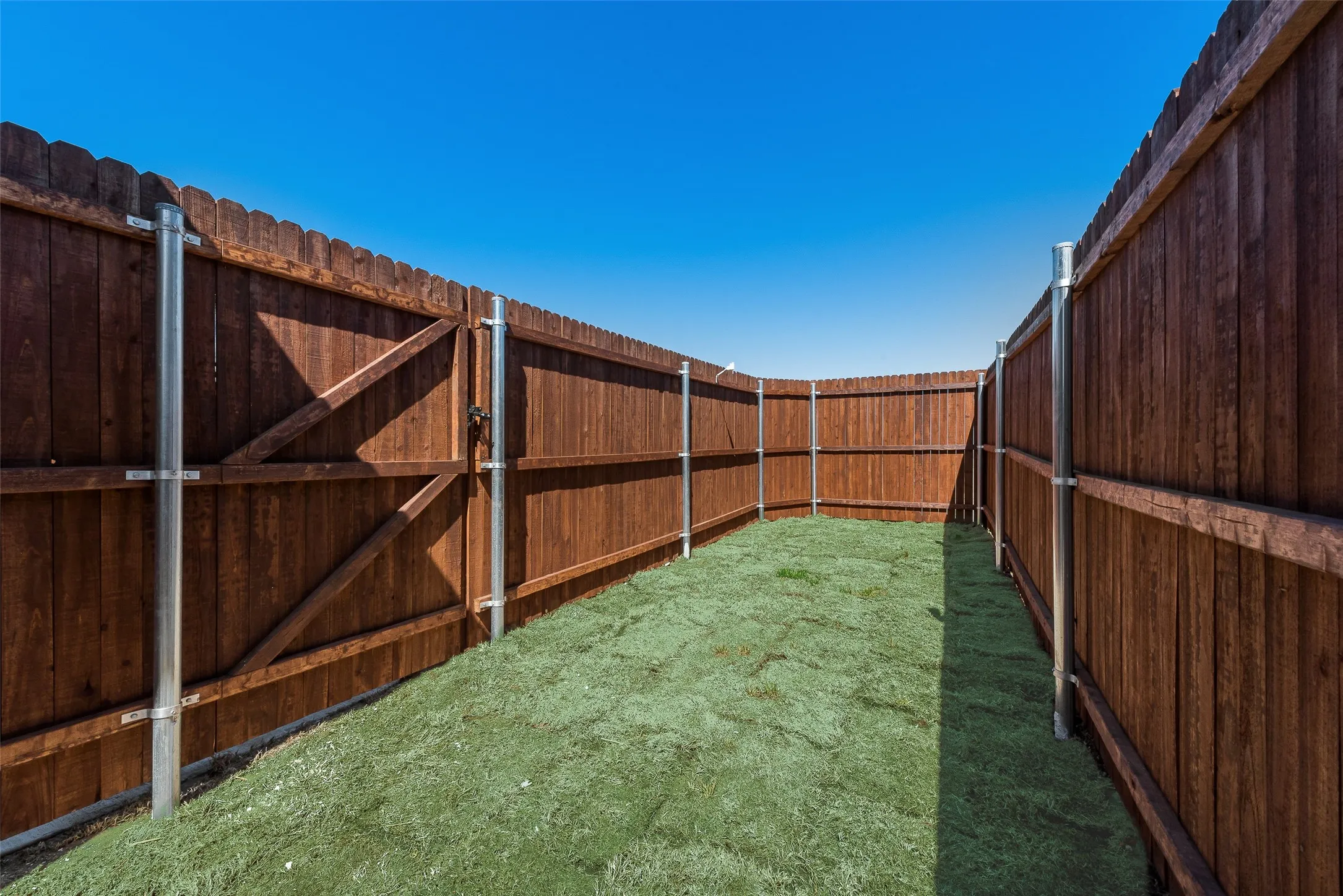 Enclosed yard space with wood privacy fencing and a grass lawn