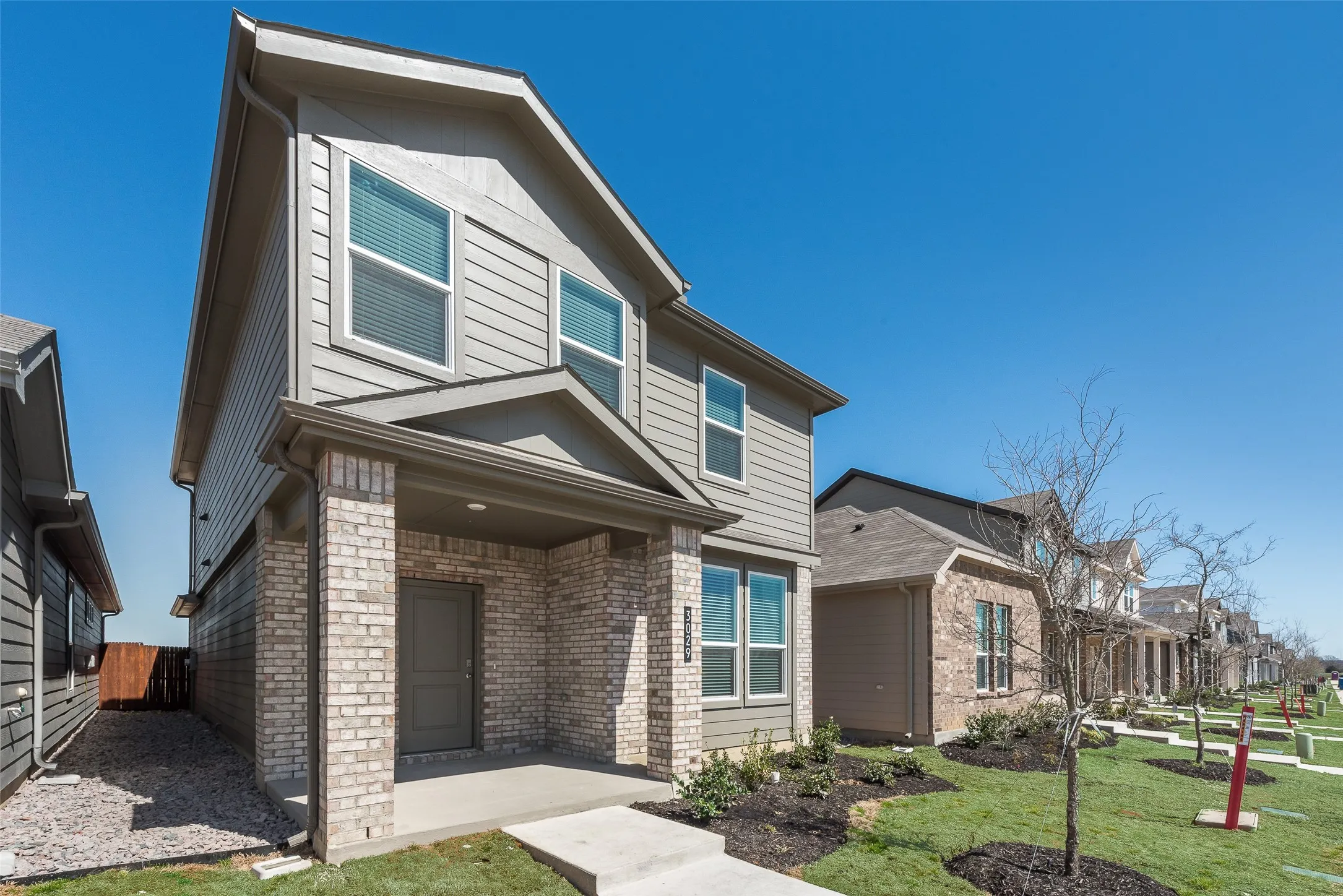 Two-story residence featuring a brick and siding exterior, covered front entry, and multiple windows with blinds