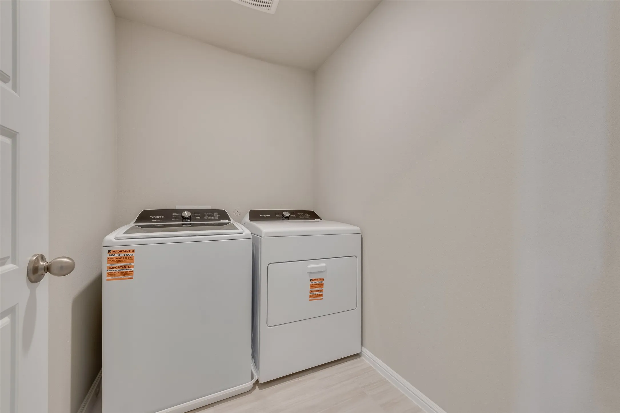 White washer and dryer appliances, light-toned walls, and wood-finish flooring