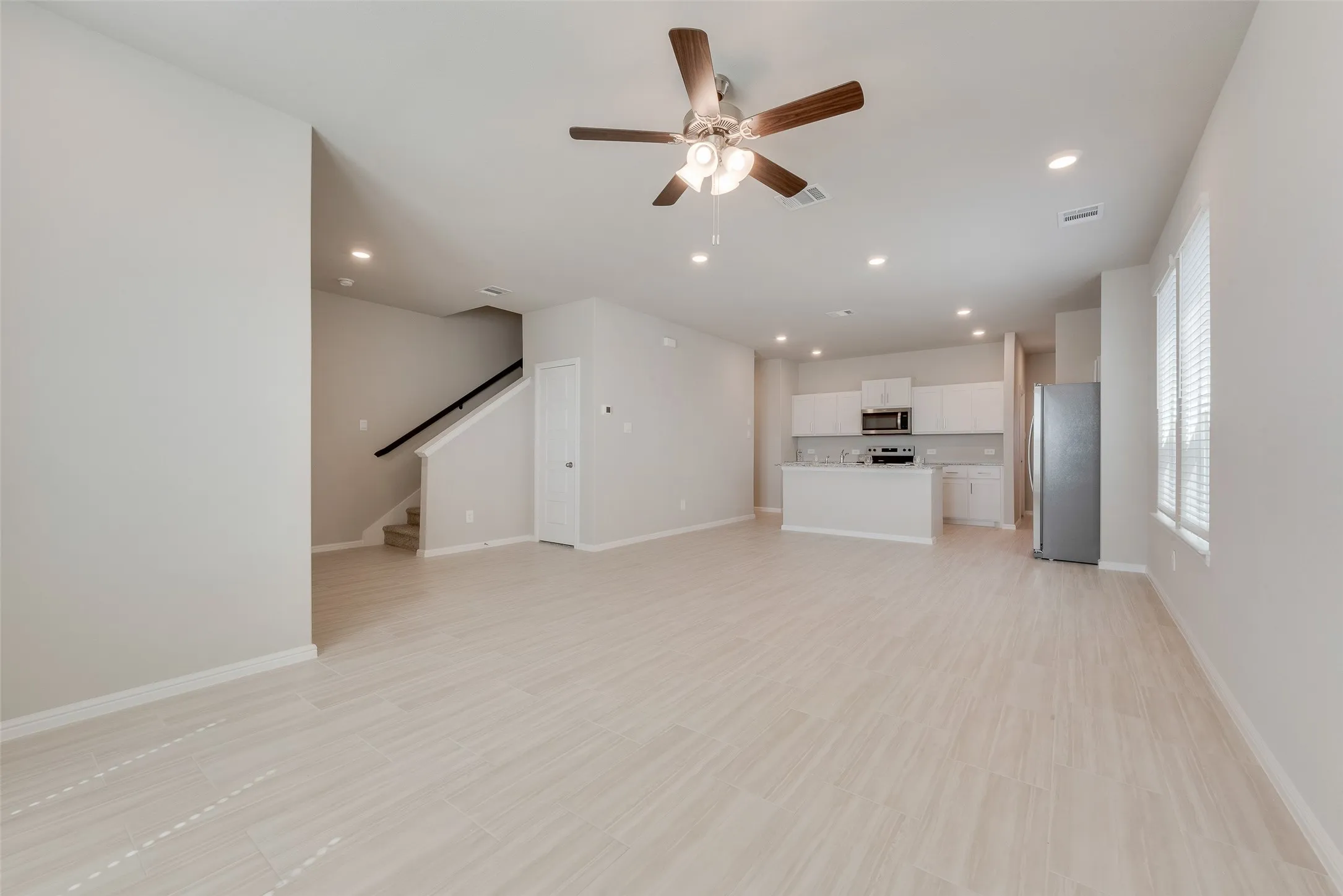 Open-concept living space with tile flooring, recessed lighting, and a ceiling fan