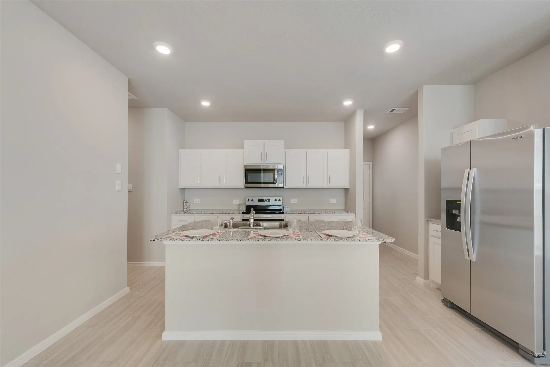 Kitchen featuring a central island, white cabinetry, stainless steel appliances, and recessed lighting