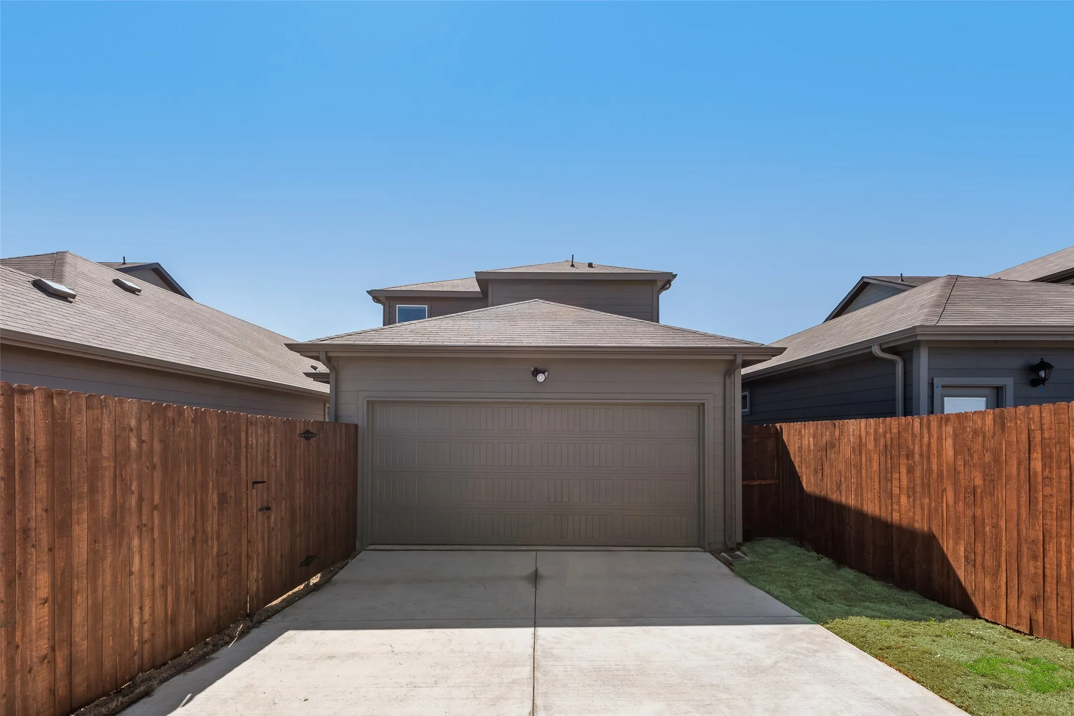Attached two-car garage with a concrete driveway and privacy fencing