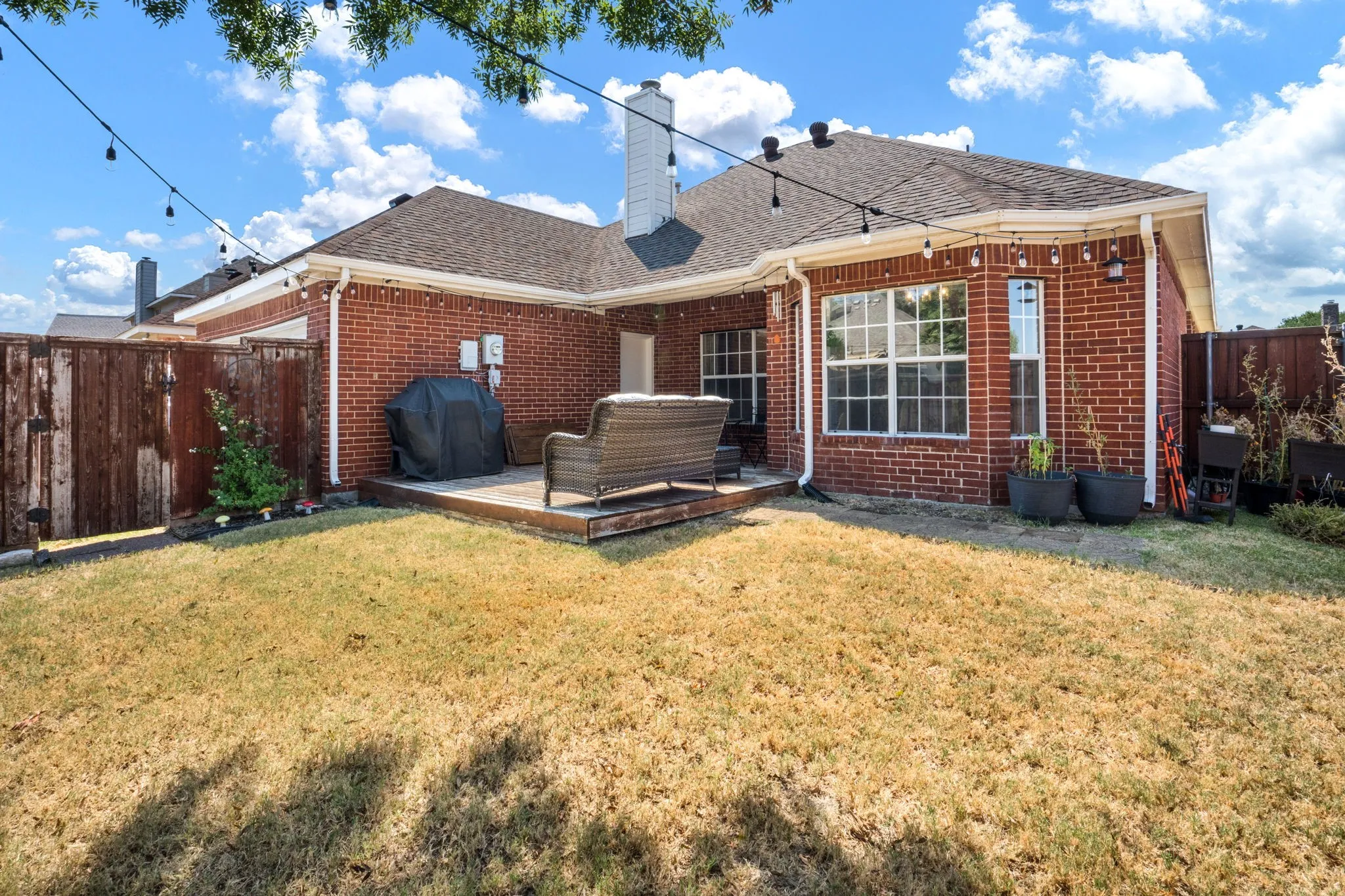 Brick exterior featuring a wooden deck and a private perimeter fence