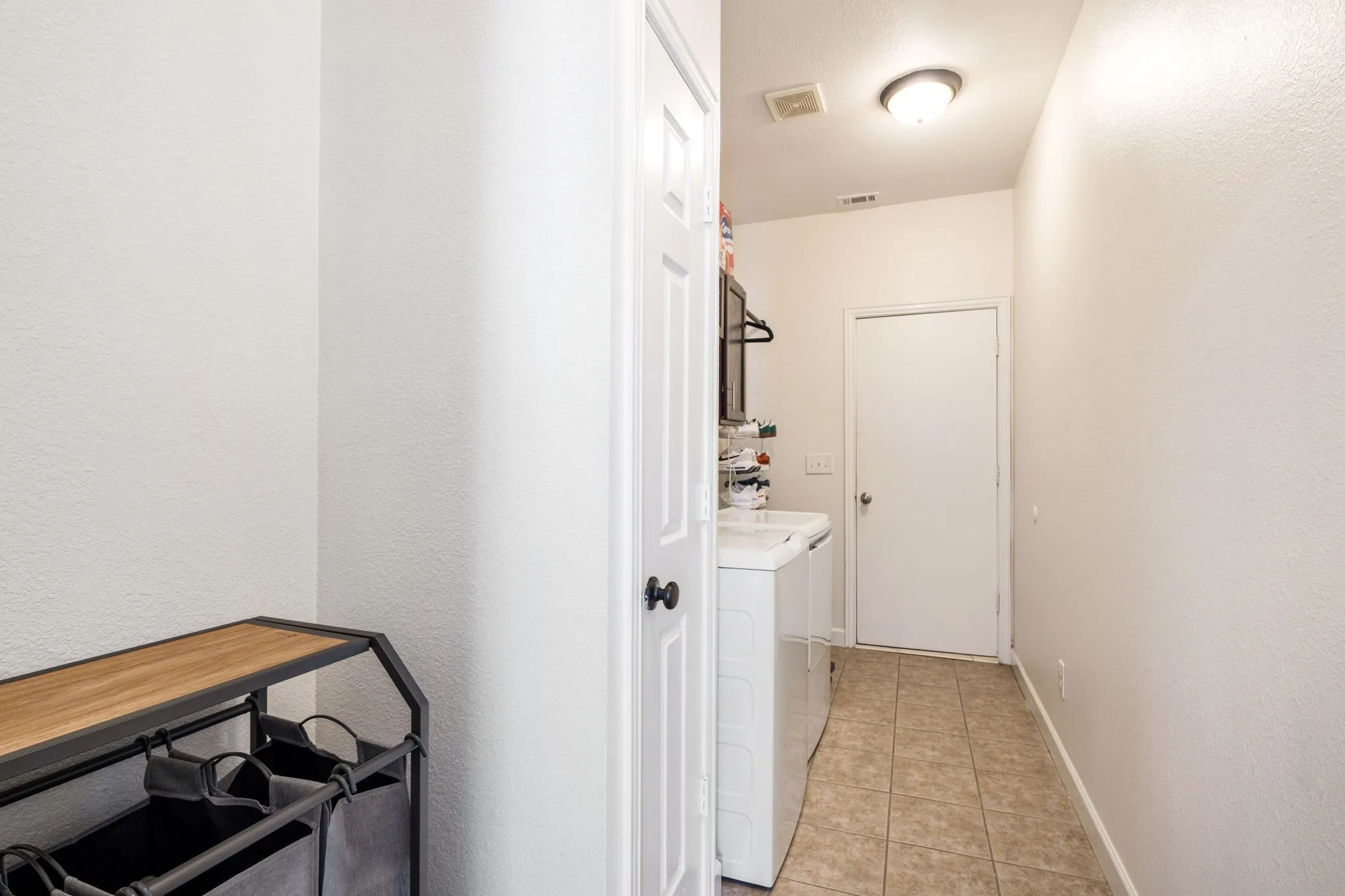 Laundry area featuring tile flooring, a ceiling-mounted light fixture, and white walls