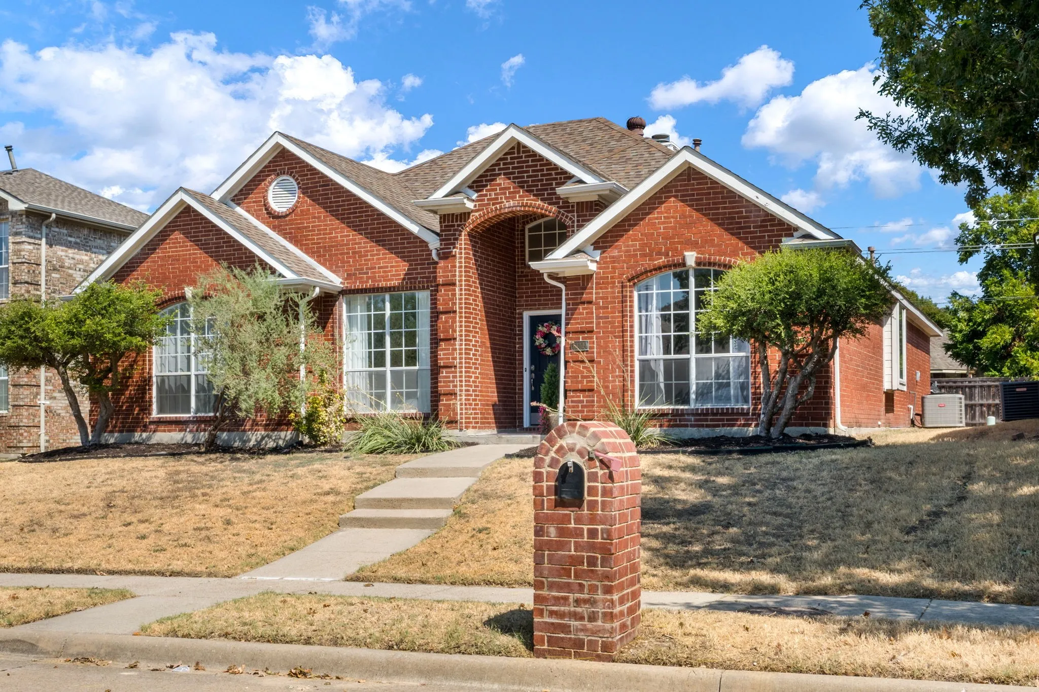 Brick exterior with a gabled roofline, arched entry, and prominent bay windows